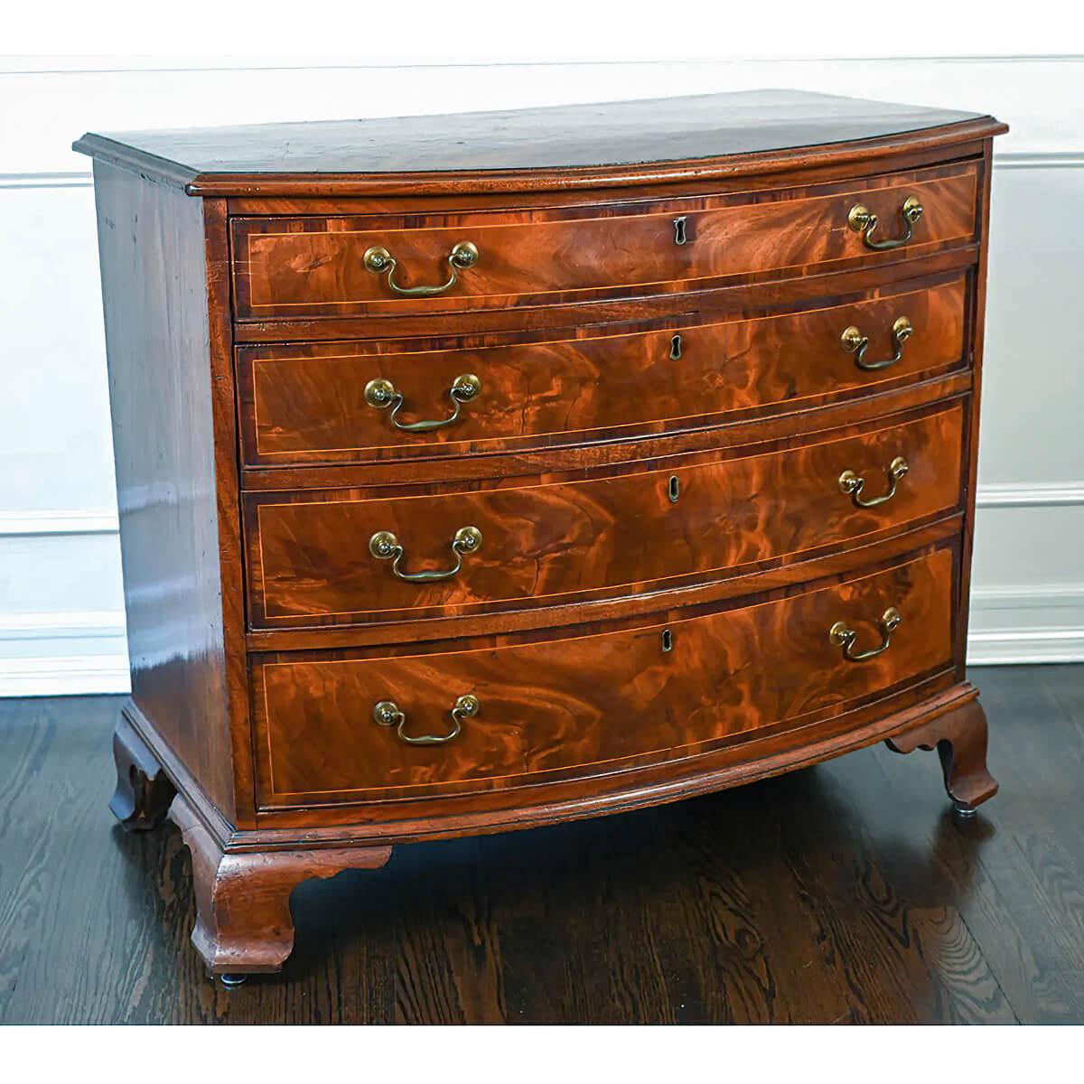 A fine George III mahogany bowfront chest of drawers. This 18th century English dresser has four graduated, with crotch mahogany and satinwood line inlaid cross banding, with the antique brass bail handles raised on fine ogee bracket feet.