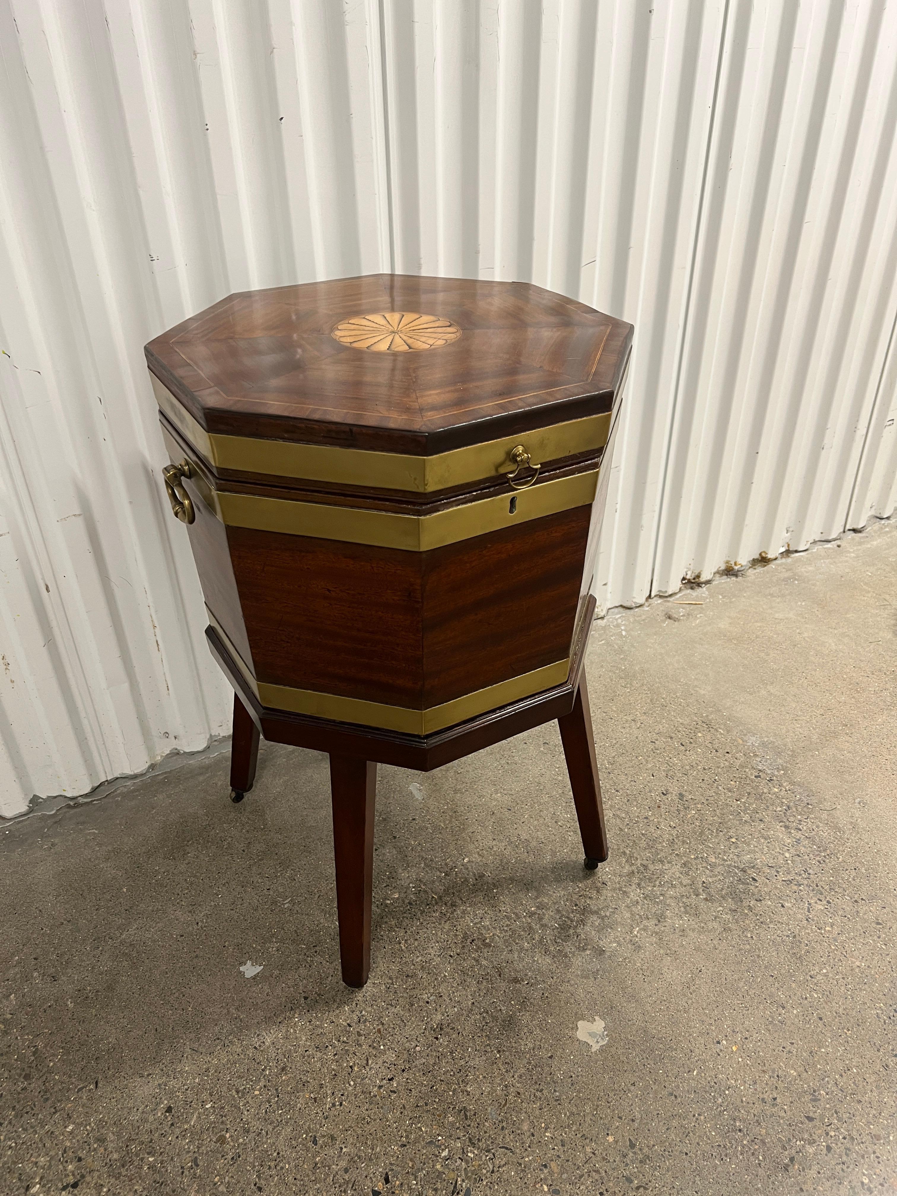 English, circa 1820.

Beautiful octagonal hinged top opening to an aluminum liner for ice or storing bottles by themselves. Exterior featuring a conforming brass strapped case and fine detailed burst inlay to the top lid. Brass handles to each side