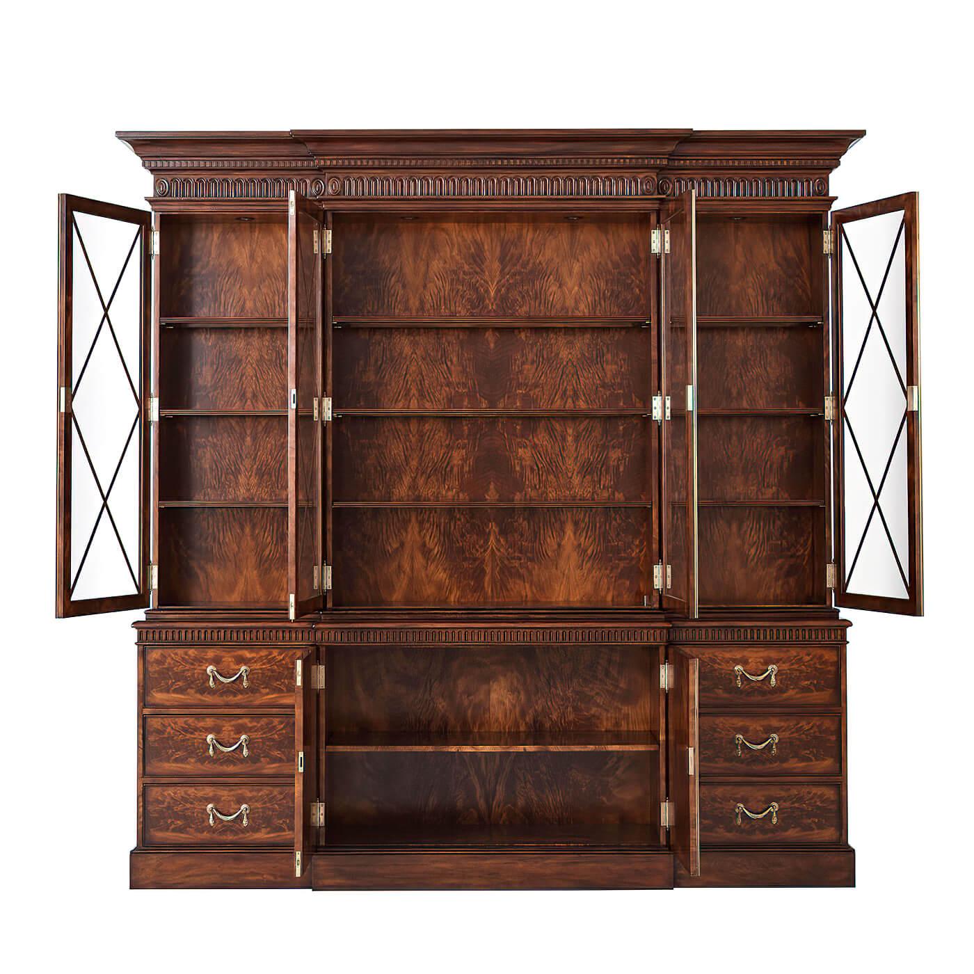 A George III style mahogany breakfront bookcase, the upper sections with a molded cornice above a fluted frieze ornamented with dentils and oval rosettes, the bold diamond lattice astragal glazed doors enclosing reeded edge shelves above two