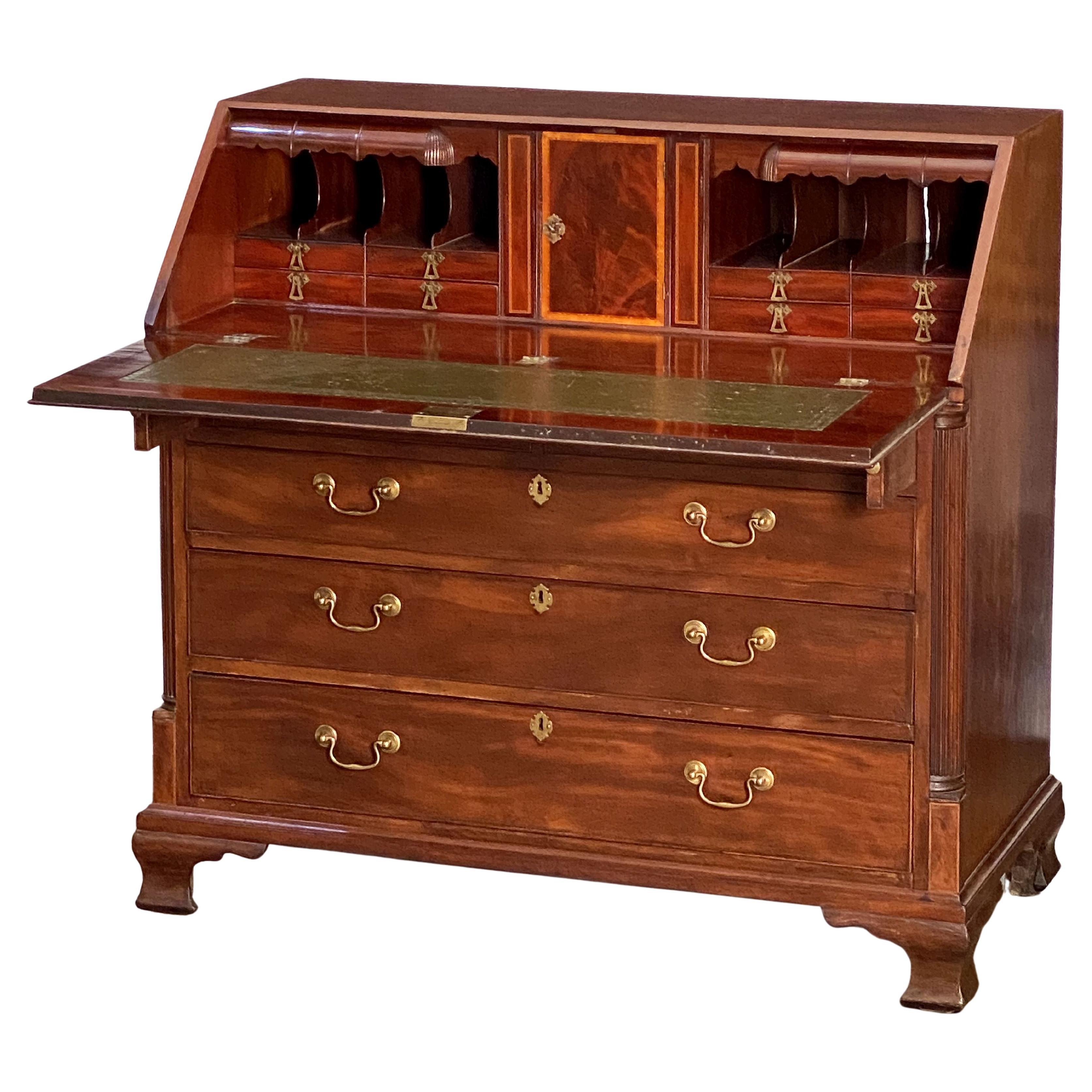 A fine George III slant top desk or bureau secretary chest of patinated mahogany, c.1770 - an inlaid slant front drops to reveal a series of small drawers and document compartments, over two short drawers and three graduated long drawers, the