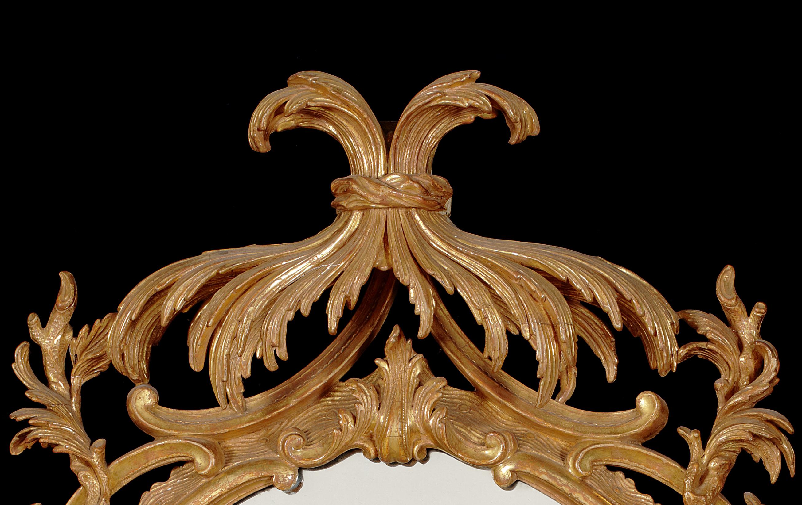 George III carved giltwood mirror
The oval plate surmounted by a tied leaf canopy cresting above icicles, branches and acanthus leaves to the sides, with double 'C' scroll and pierced fret carved apron below, 68cm wide, 120cm high.