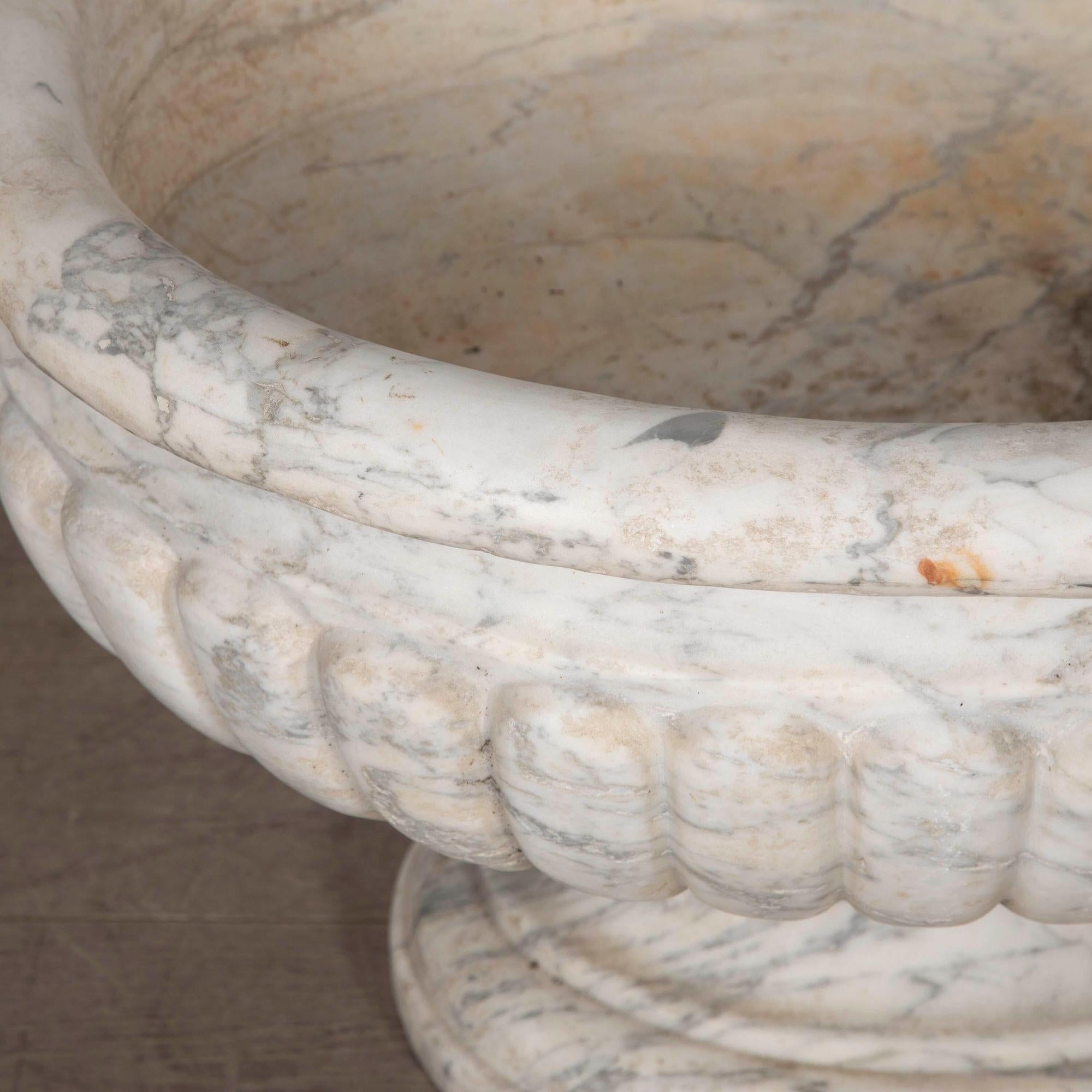 Glorieuse citerne en marbre de Carrare du début du 19e siècle, de grandes proportions.
La coupe ovale à godrons, audacieusement sculptée, repose sur un socle finement détaillé.
L'ensemble est magnifiquement tactile et poli par l'usure du temps, avec