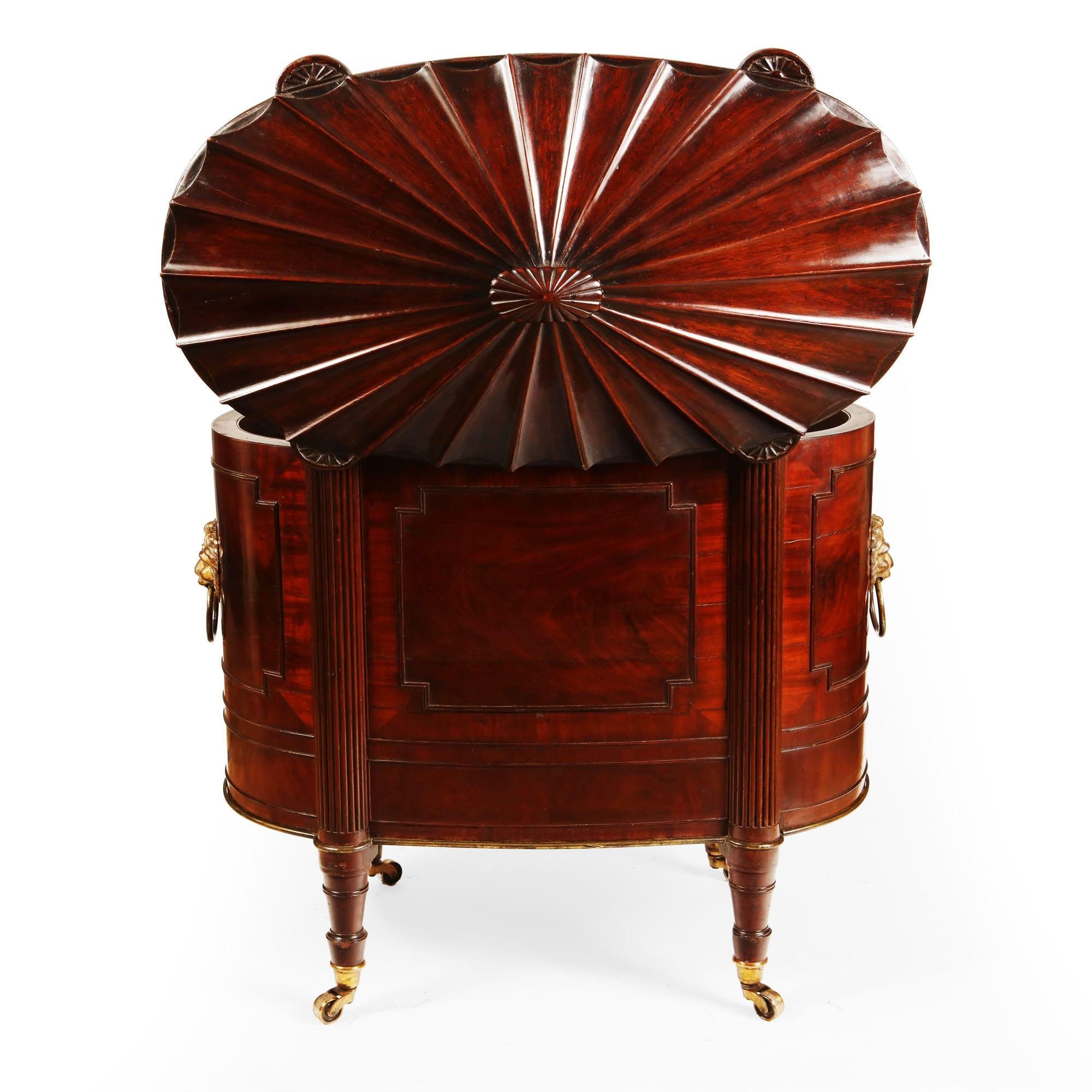 Nicholas Wells Antiques are delighted to offer this exceptional mahogany cellarette is constructed in an oval form with a superb hinged lid, decorated with tapering flutes and edged with a reeded border and inset carved patrae to the top of the four