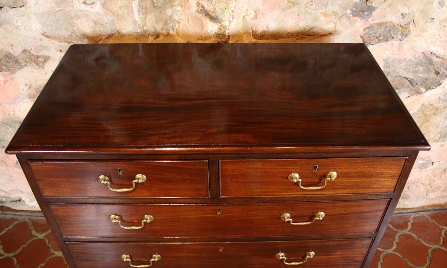 George III figured mahogany chest of drawers with two short drawers over three long oak lined drawers with original brass swan neck handles.