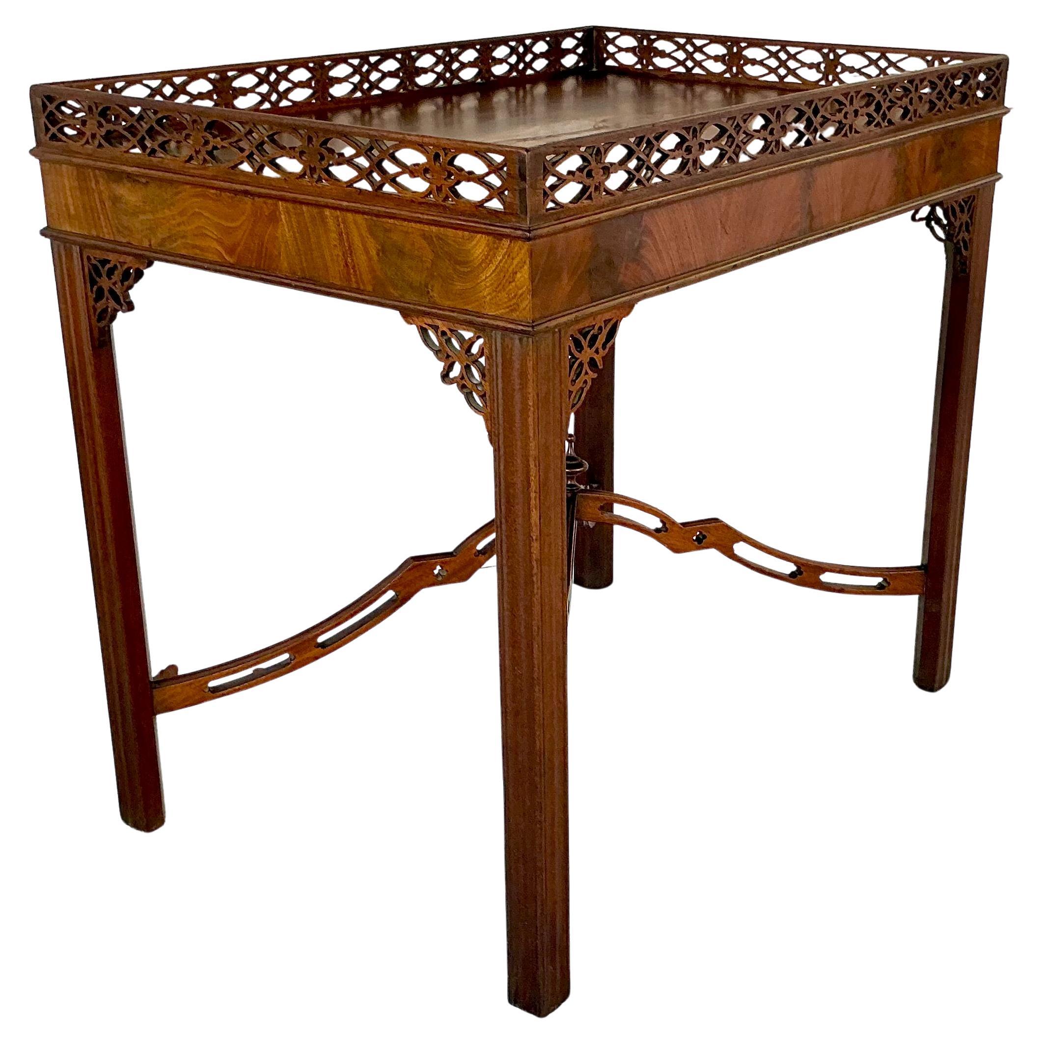George III Chippendale Carved Mahogany Silver Table. Table features a fixed tray top with an intricately pierced gallery in an interlaced lattice pattern. The apron is clean and understated, allowing the gallery and corner brackets to shine.