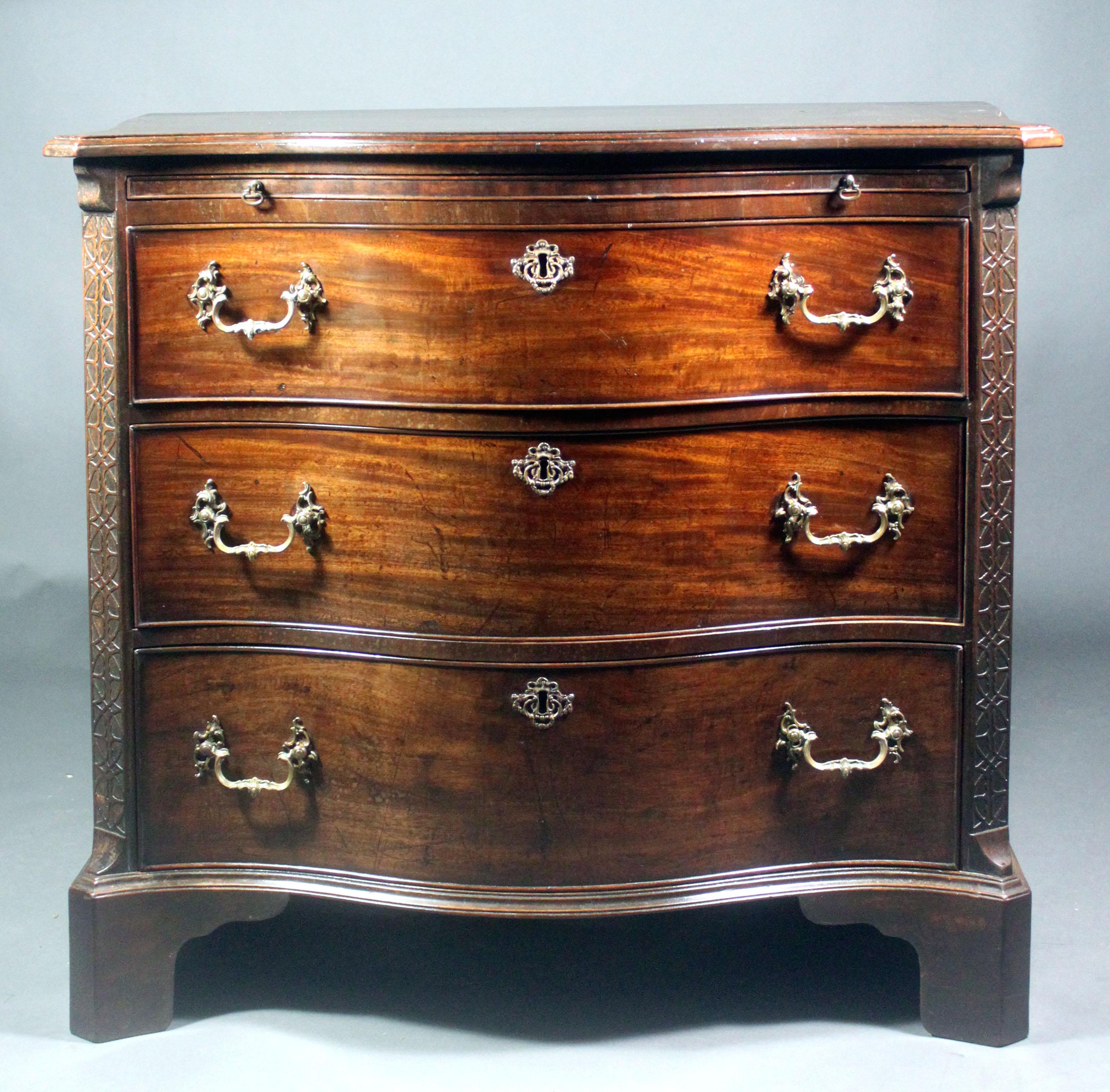 A fine George III Chippendale period serpentine chest in figured mahogany of an original colour and patina. Good features include the brushing slide, canted corners with blind fret and the original carrying handles. The old rococo swan neck handles