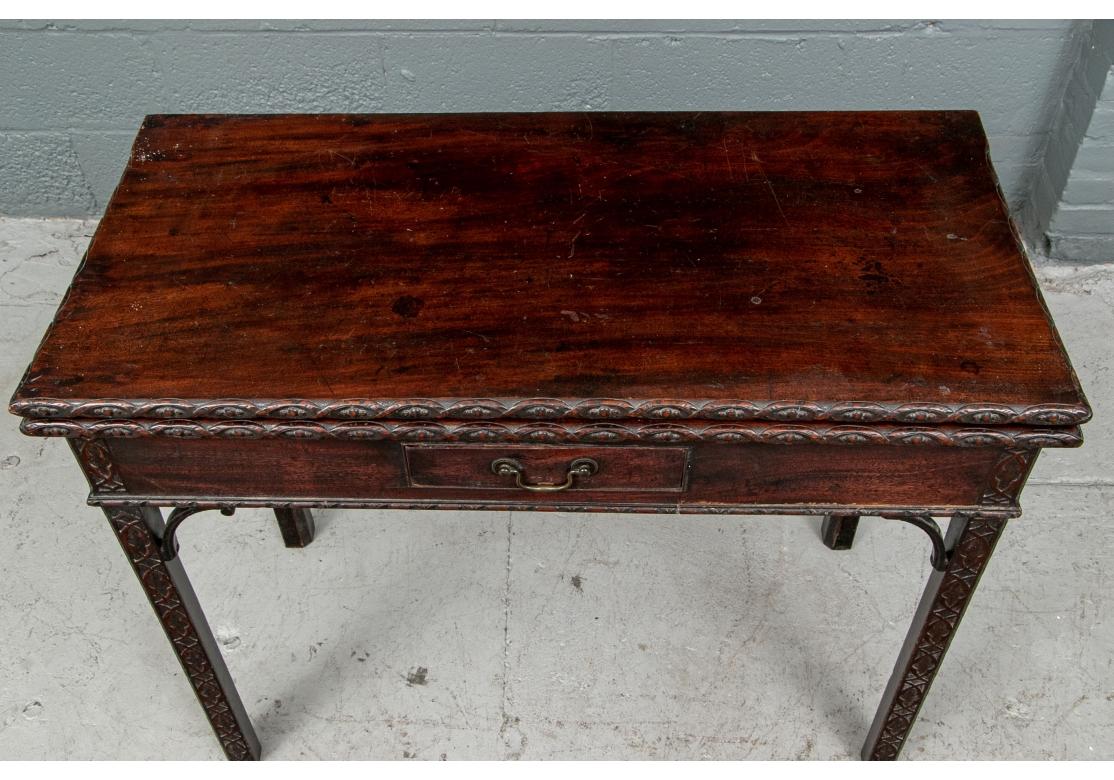 A classic early 19th century Chippendale style games table with fancy fretwork all in a time-softened patina. Rectangular games table with carved top edges with hinged top. The frieze with carved molding and a single drawer on the front. Raised on