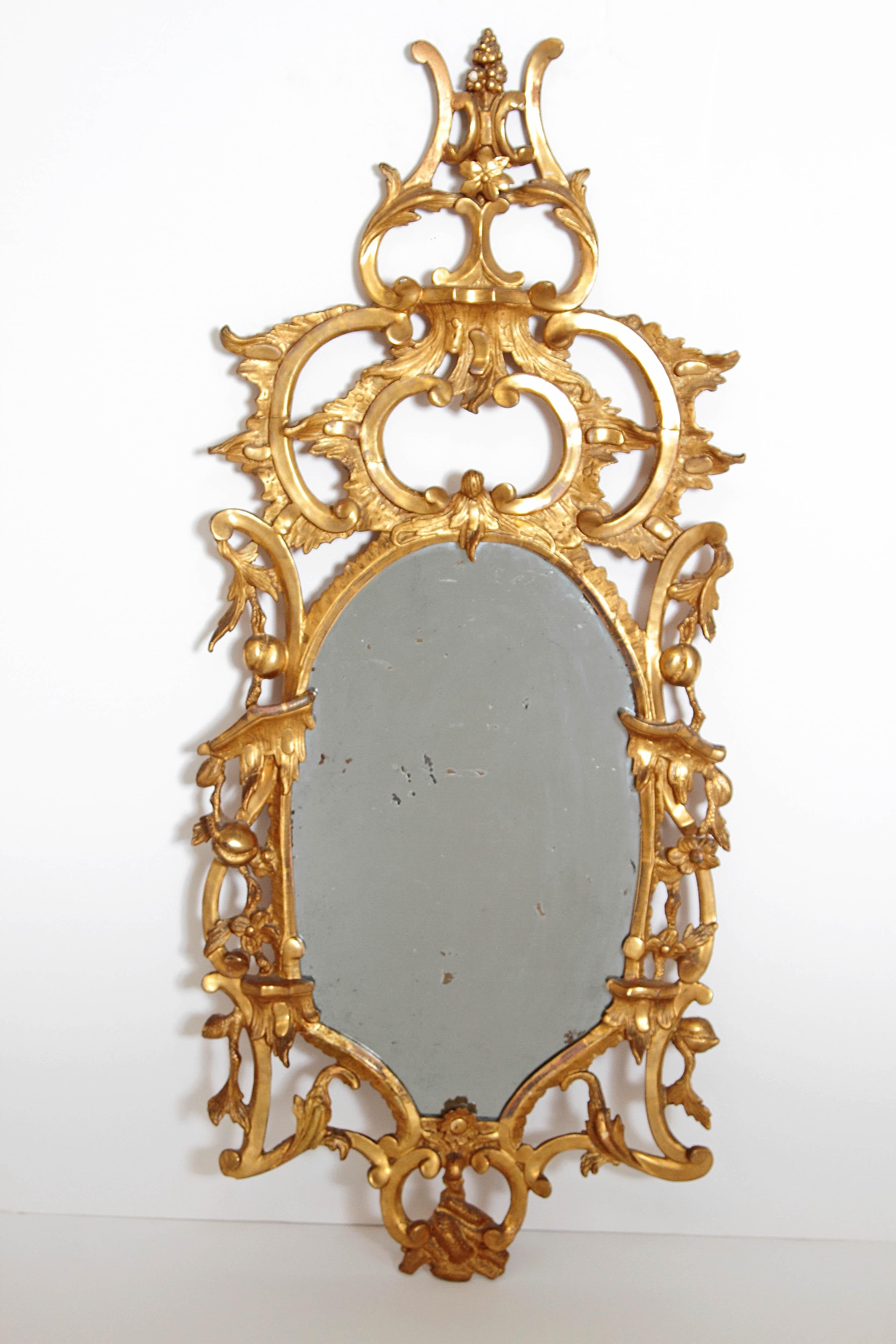 This elaborate 18th century English pier glass mirror is the ultimate statement piece. Masterfully carved with floral details, acanthus and C-scrolls, all surmounted by an architectural cresting with a finial. 18th century, England.