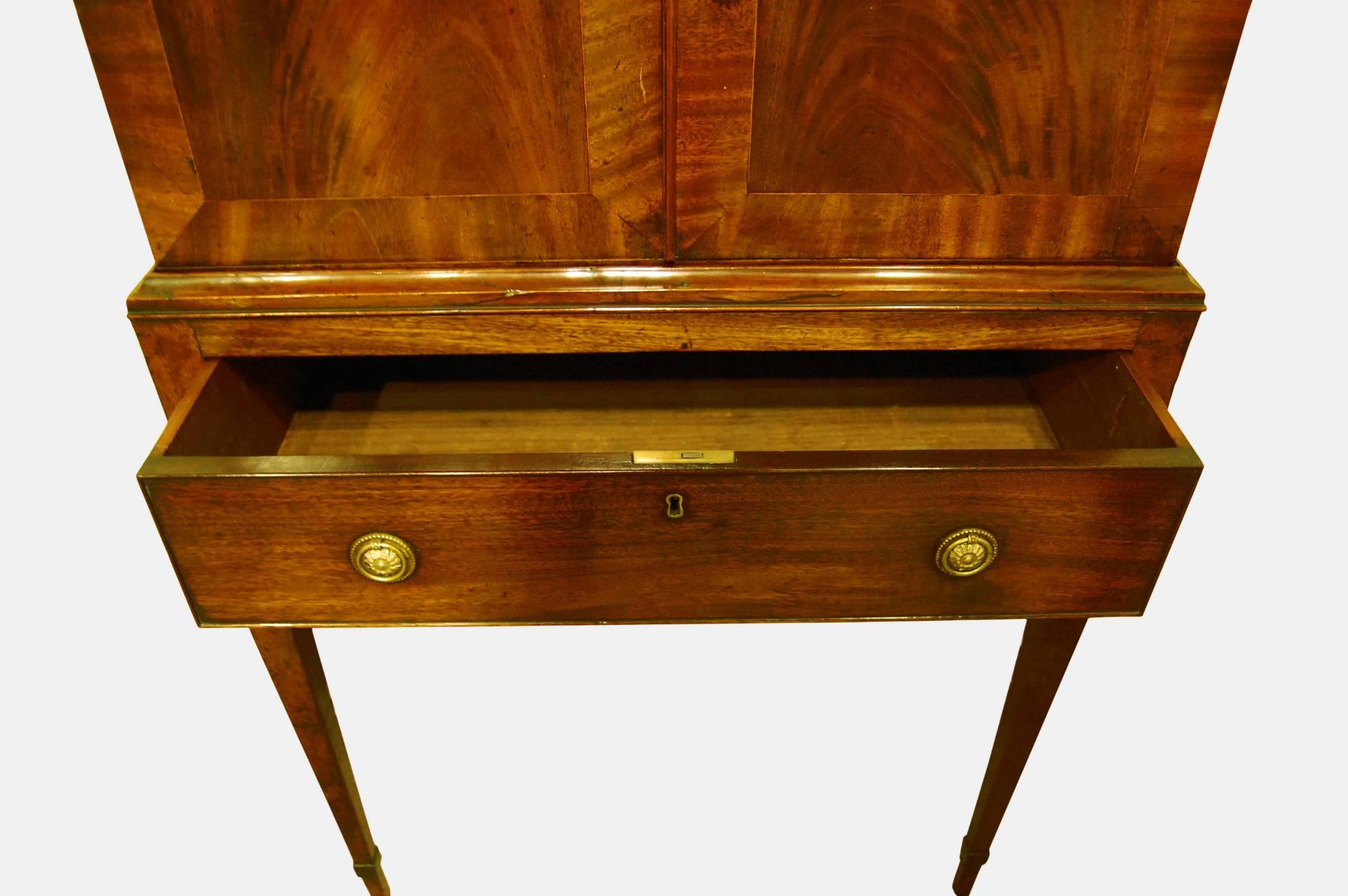 A fine George III mahogany collectors cabinet on stand, the satinwood dentil cornice above crossbanded doors enclosing eight cedar lined drawers with original gilt buckle handles, raised on a single drawer base to taper legs, circa 1775.
 