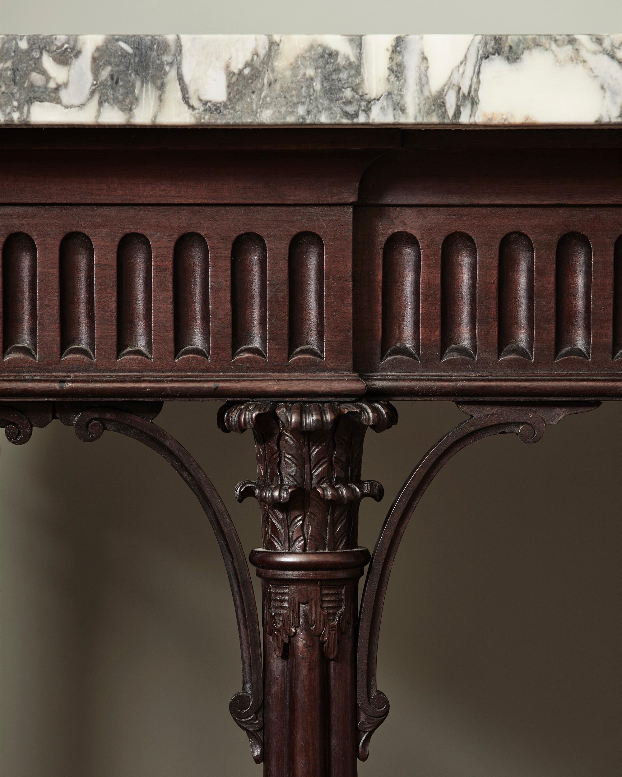A George III Console Table, with Architecturally Drawn Cluster Column Legs

With gently stepped breakfront fluted frieze, with lightly shaped and carved spandrels, with exceptionally executed cluster column legs with acanthus carved