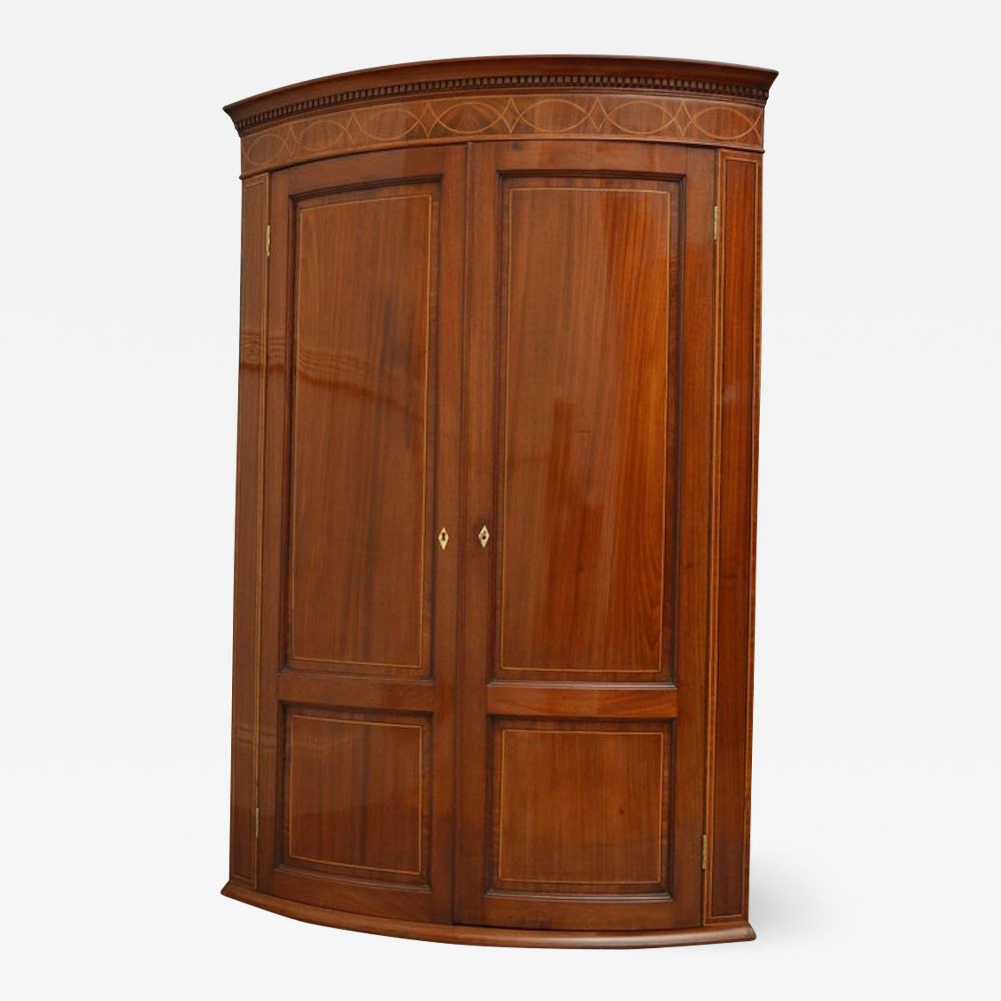 Sn2700 Good quality and very attractive Regency, mahogany corner cupboard of elegant outline, having dentil cornice above satinwood string inlaid frieze, figured mahogany double panelled doors with ivory escutcheons, enclosing 3 shelves and 2 small