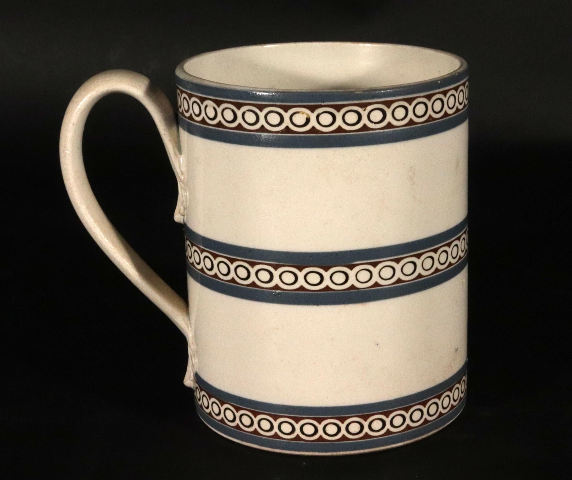 Feiner George III Creamware Krug mit emailliertem Dekor,
Englisch, um 1800

Dieser fein getöpferte Krug aus englischem Sahnegeschirr des späten 18. Jahrhunderts hat eine saubere, zylindrische Form und eine glänzende Glasur. Das auffällige Dekor