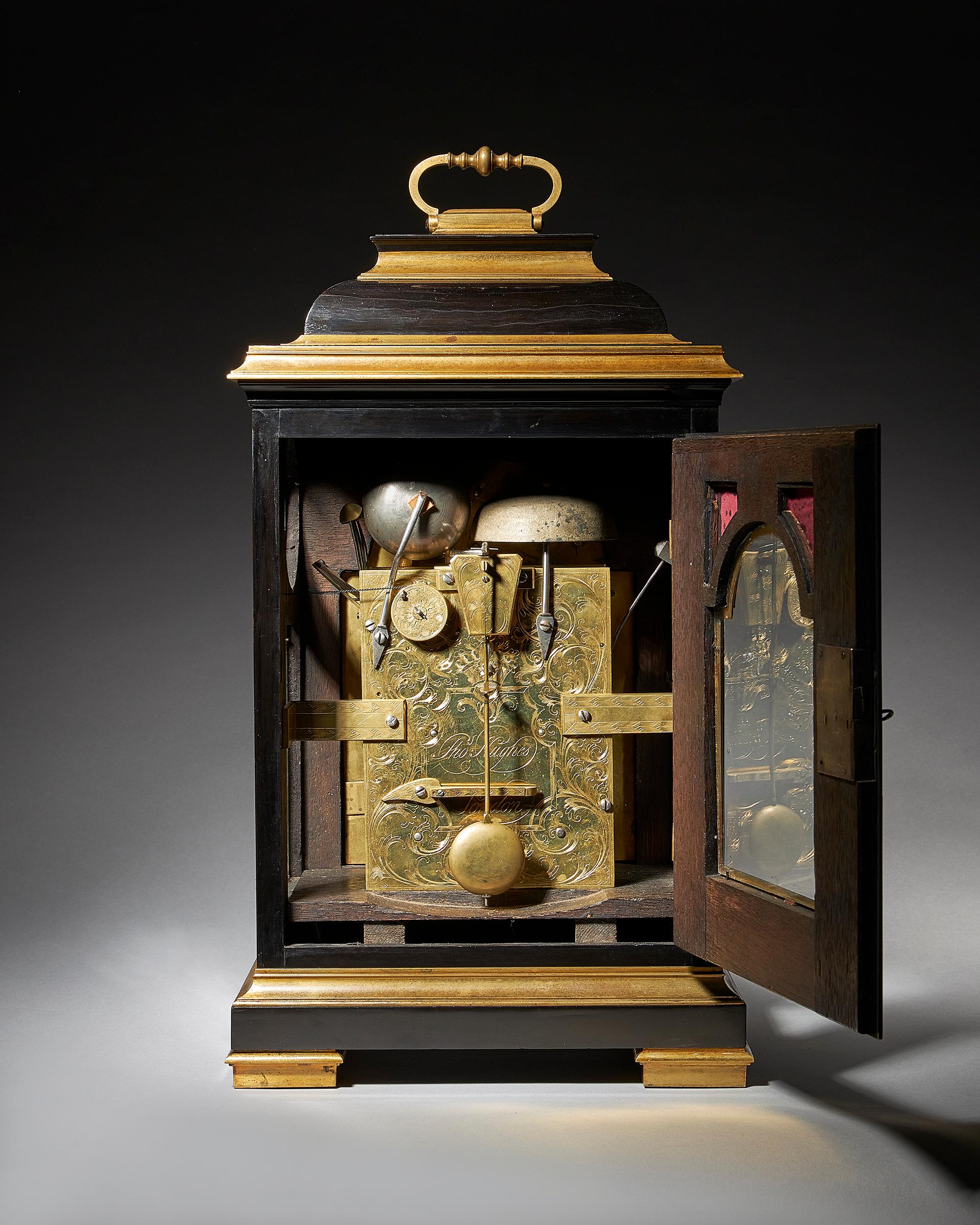 By Thomas Hughes, London

The ebony-veneered case has an inverted bell top, a design which became popular in the early Georgian period (from 1715 onwards). The case is adorned with brass mouldings and rests on shaped brass block feet. It is