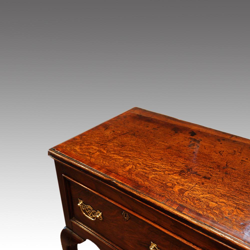 Antique oak cabriole leg dresser base
This Antique oak cabriole leg dresser base was made in the late Georgian period, circa 1820.
The dresser is made of oak with fruitwood crossbanding and is fitted 3 drawers to the front with brass fretted swing