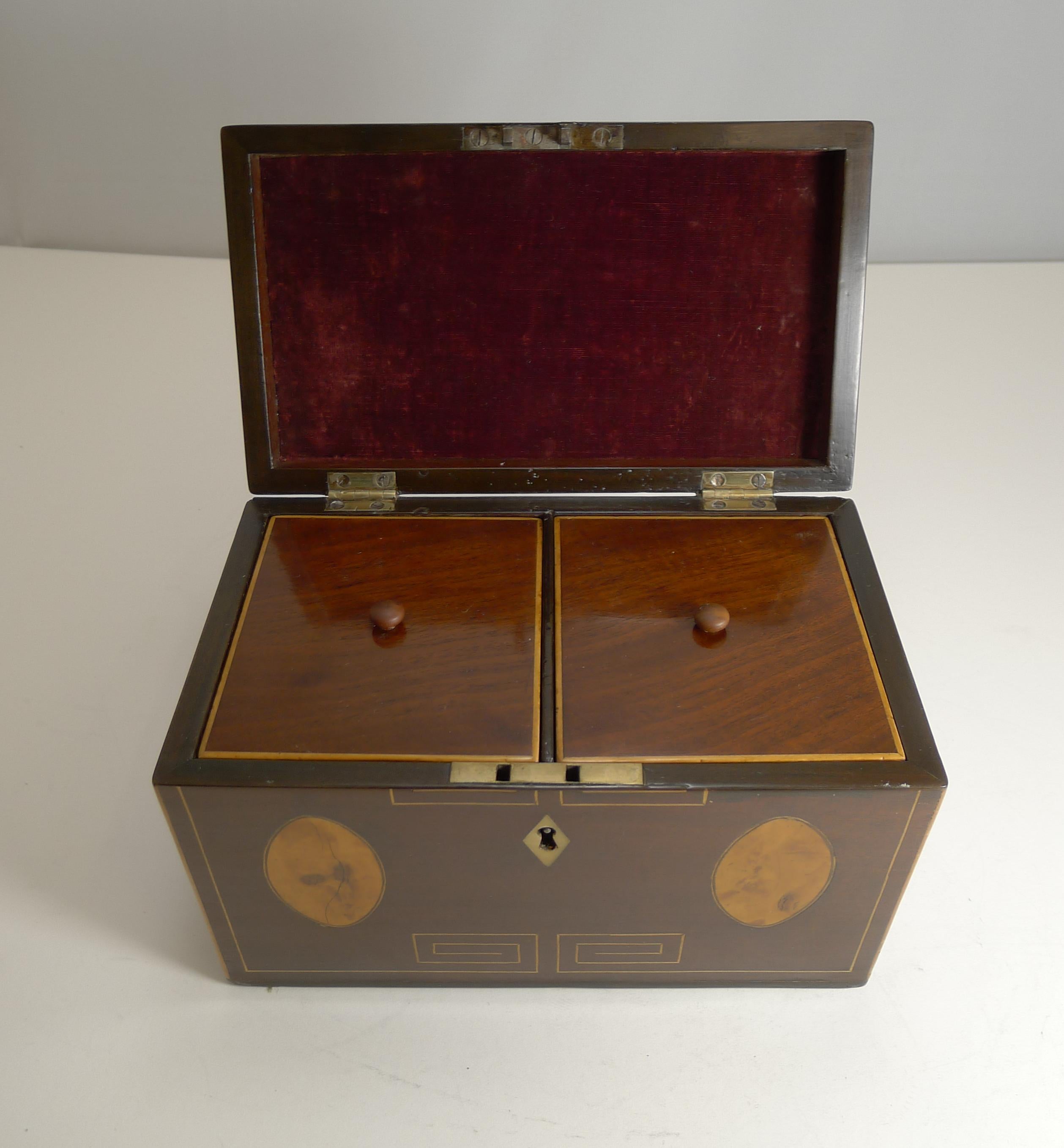 A stunning and most unusual Georgian tea caddy made from mahogany and inlaid with four oval satinwood panels.

Another unusual feature is the fine Greek Key inlay to both the the lid and top.

The interior has two lidded compartments later