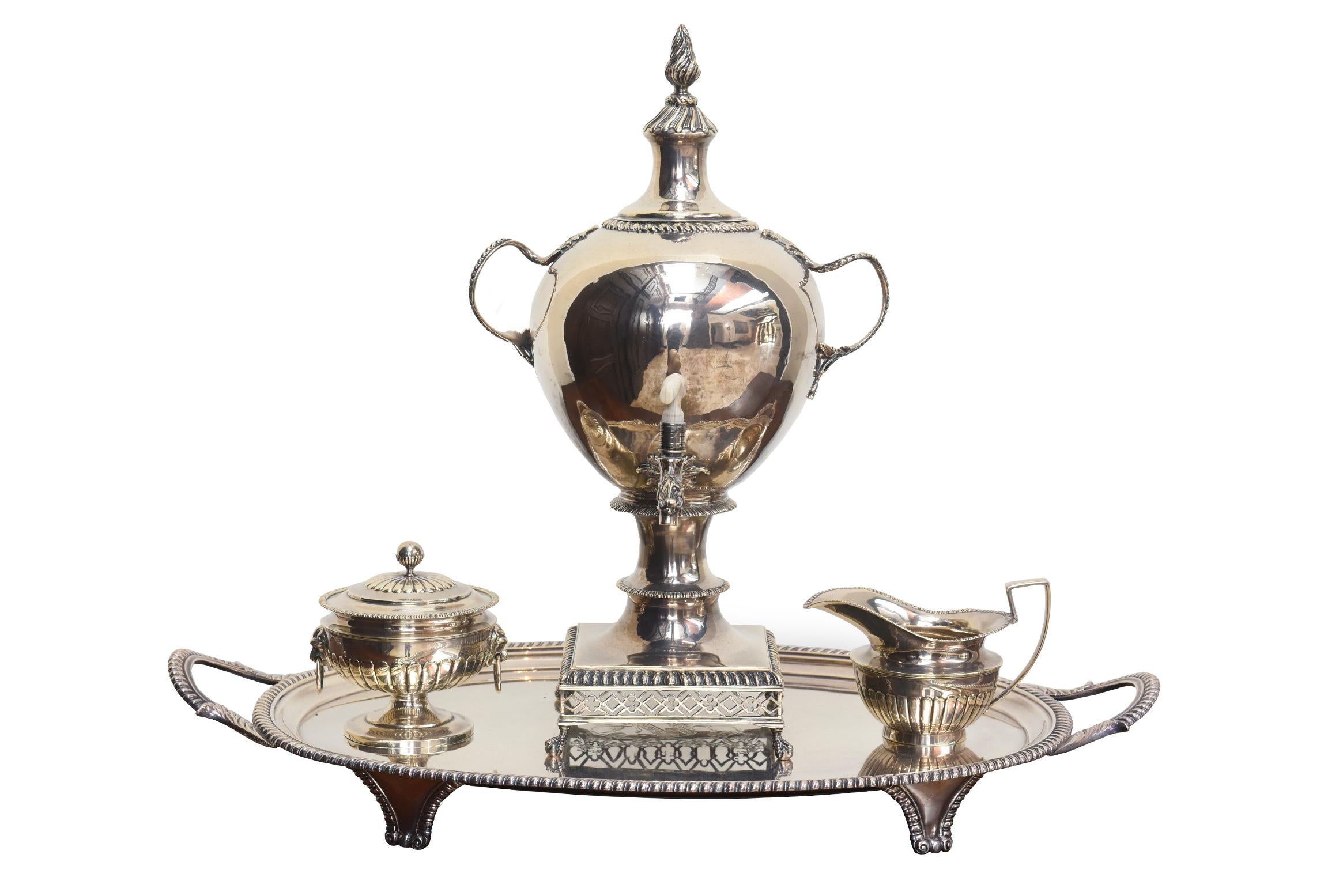 Questo elegante set da tè inglese di Giorgio III comprende una teiera in argento, un bricco per il latte caldo e una zuccheriera, completati da un'urna da tè in argento e da un cestino sfaccettato placcato in argento. Il set è splendidamente