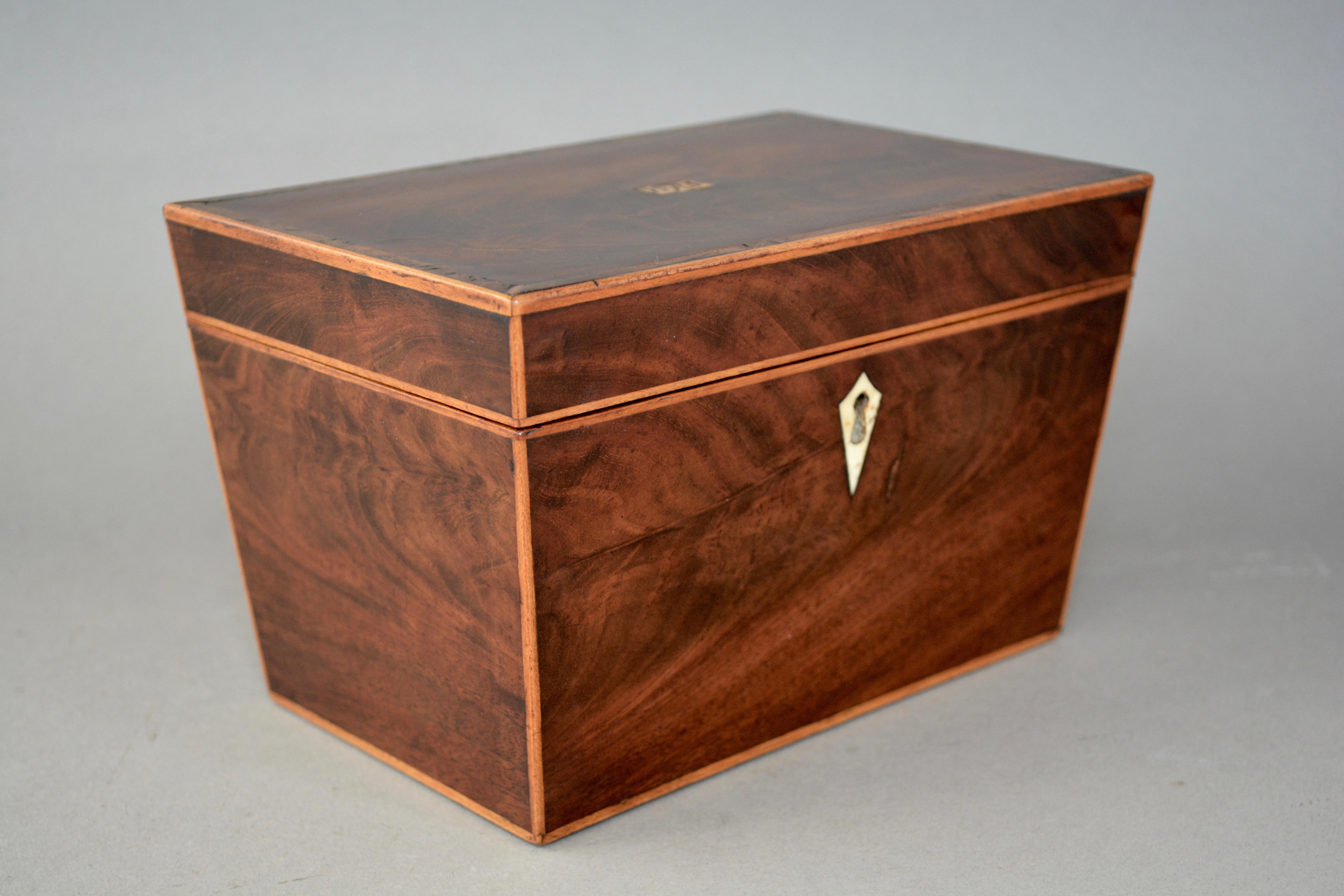 A charming and unusual George III canted side tea caddy. Hand made from flamed mahogany with yew wood cross banded top and boxwood strung edges. The box retains the original bone escutcheon and cartouche. English and dating from circa 1810.