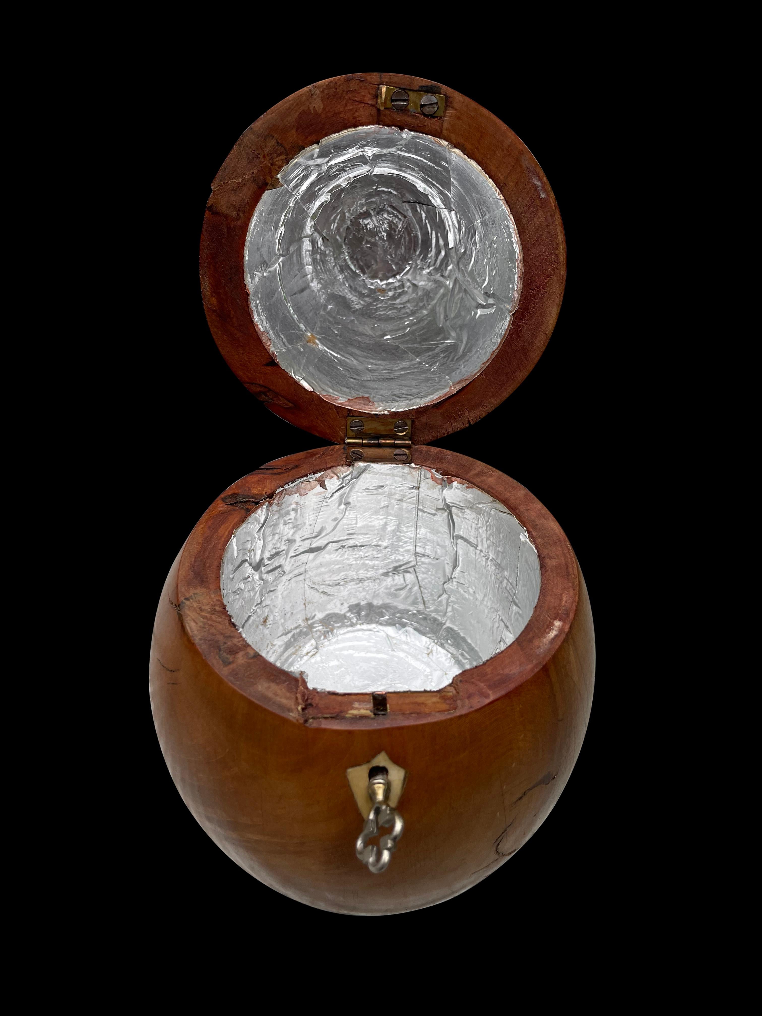 A superb George III fruitwood pear-shaped tea caddy late 18th century with a stem finial and metal escutcheon, opening to a void foil interior.

     