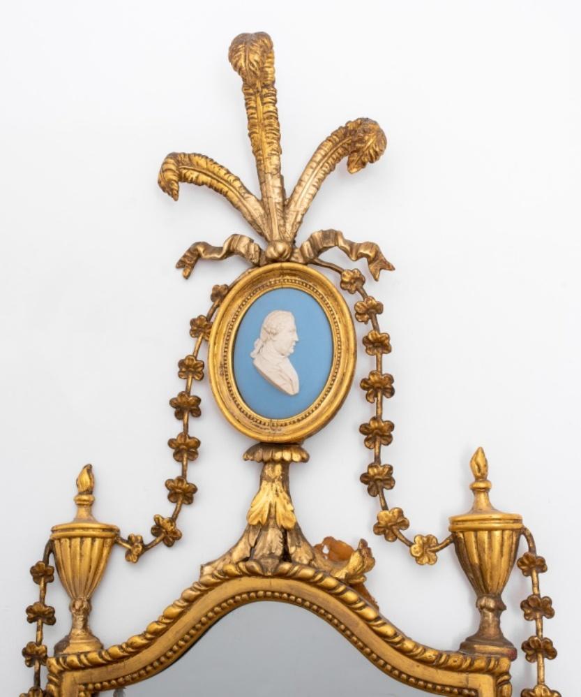 George III gilt wood jasperware mounted mirror, circa 1780 or later, with Prince of Wales feathers atop a gilded cartouche centering a Wedgwood blue jasperware oval silhouette of a right-facing gentleman above a shield-shaped mirror with conforming