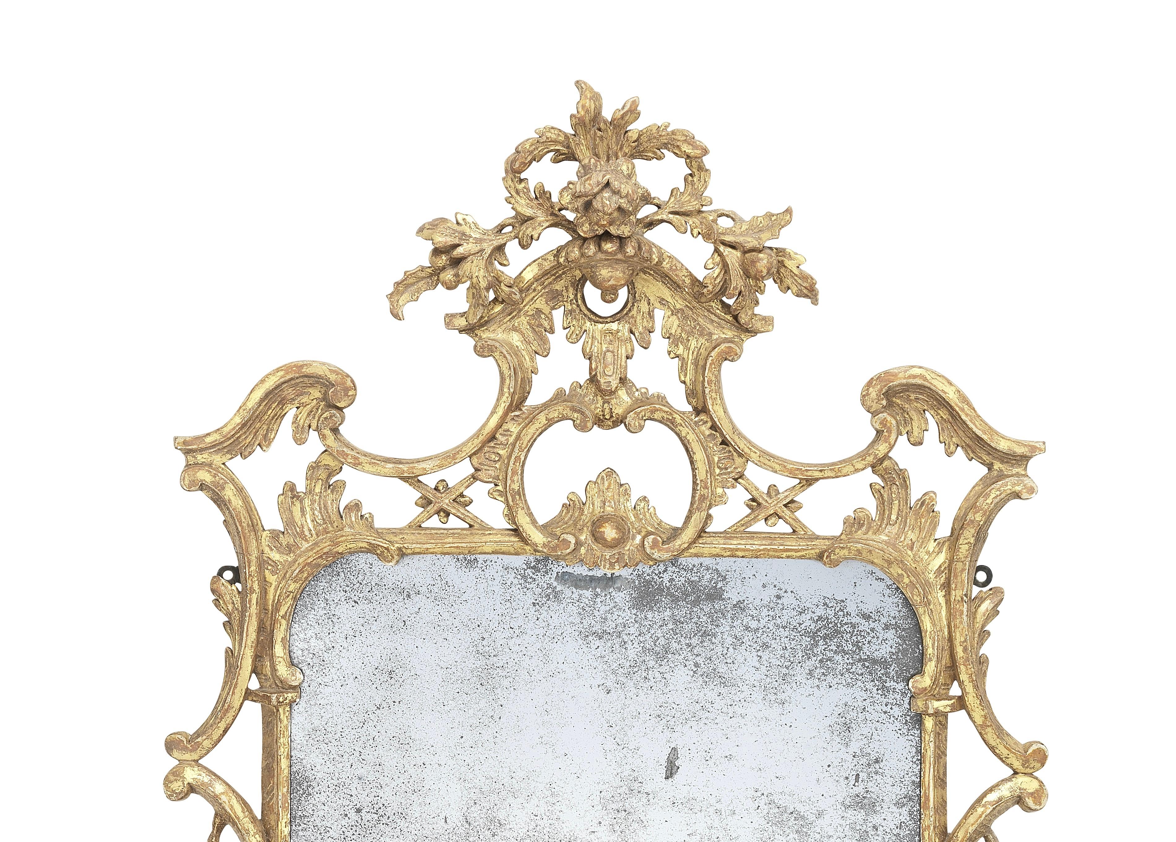 An early George III carved giltwood mirror in the manner of Thomas Johnson, circa 1760.

The period mercury mirror plate within a moulded fluted frame is flanked by cascading native flora. The carved upper C-scroll corners are pierced and