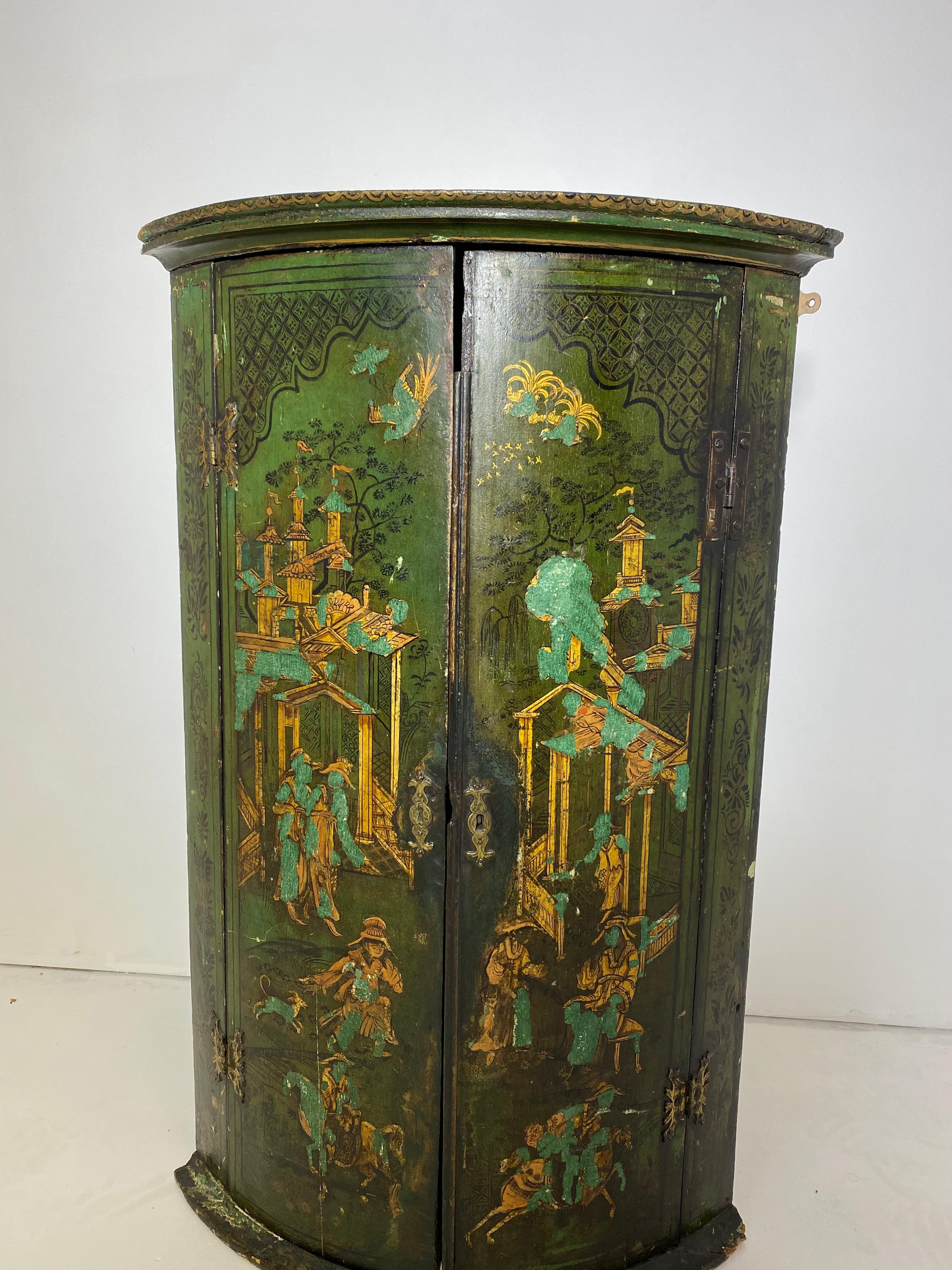 George III green-lacquered hanging bowfront corner cabinet. 4th quarter 18th century. Fitted with two cupboard doors, each with elaborate figural oriental scenes, on a molded plinth base.