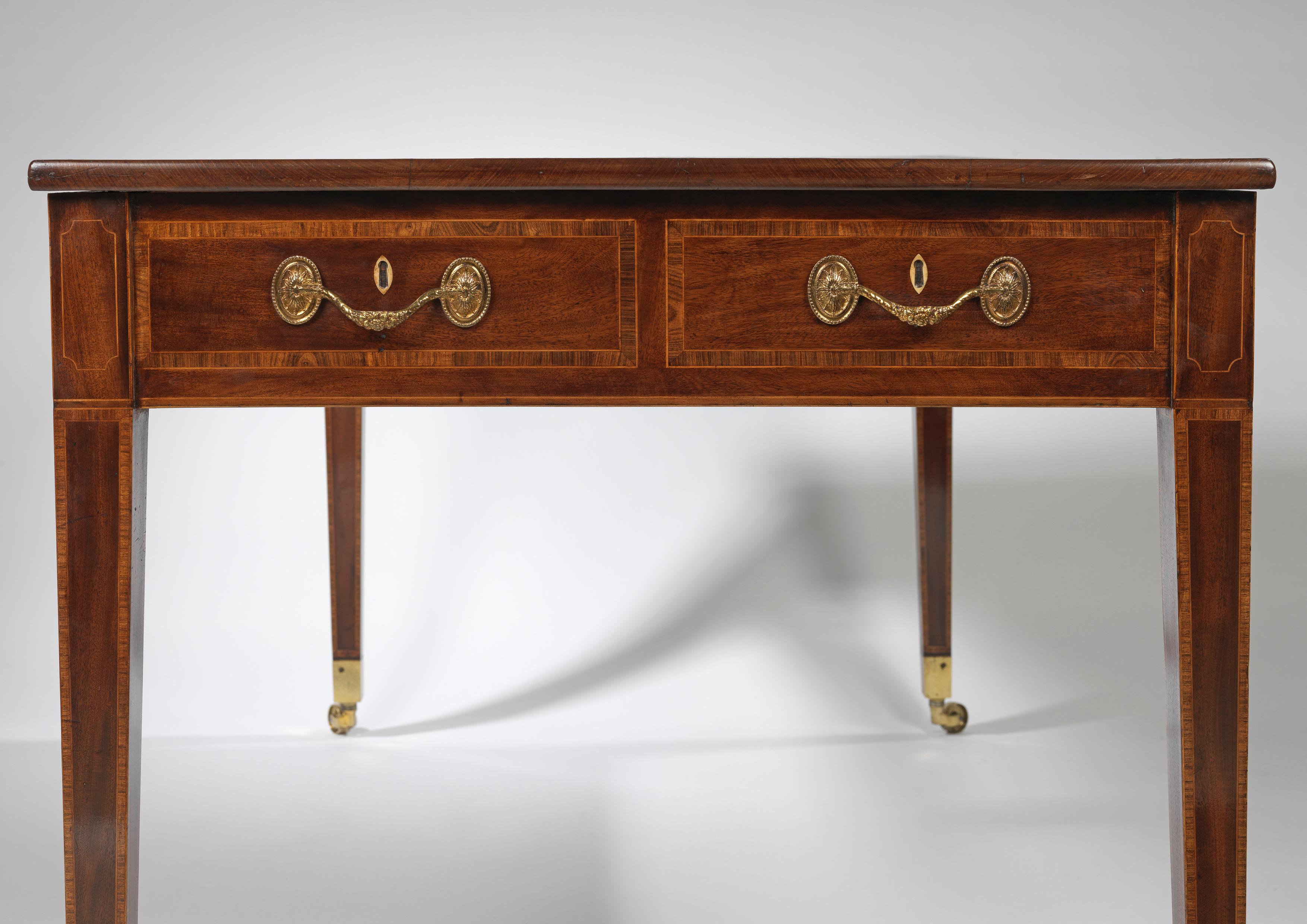 A fine late 18th century Hepplewhite period mahogany writing table, the crossbanded rectangular gilt tooled dark brown old leather lined top above three short cross banded drawers on both sides, retaining their original swag handles, bone