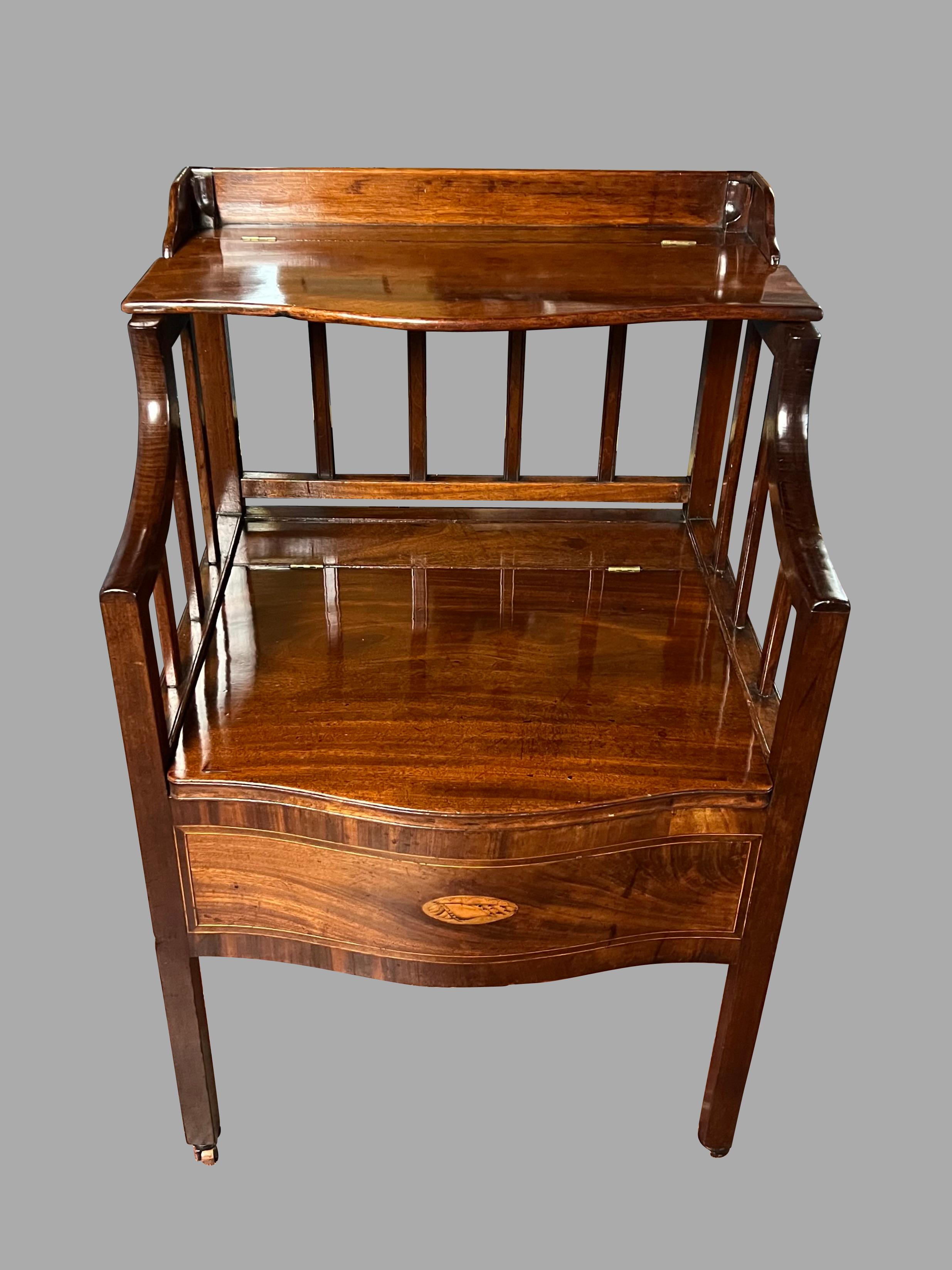 An English inlaid mahogany bedside commode of serpentine form, the front panel embellished with a well-executed satinwood inlaid conch shell. The sides and back consist of spindles and the piece rests on square legs ending in wooden casters. The