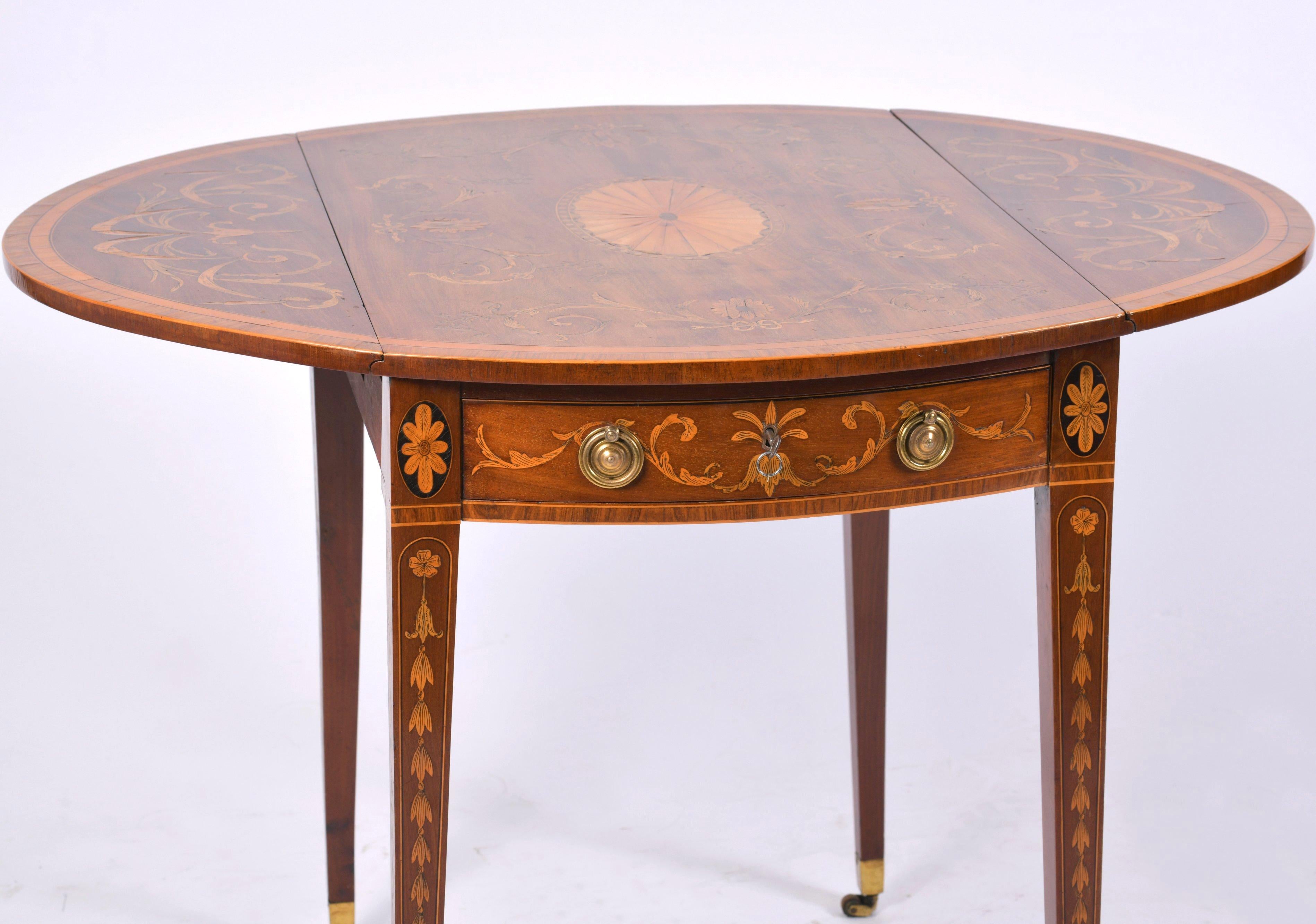 This outstanding and excellent quality George III Inlaid Pembroke table features an ornate design of satinwood inlay detailing of scrolls and floral designs on tapered legs finished with brass end caps and castors. The table has one working long