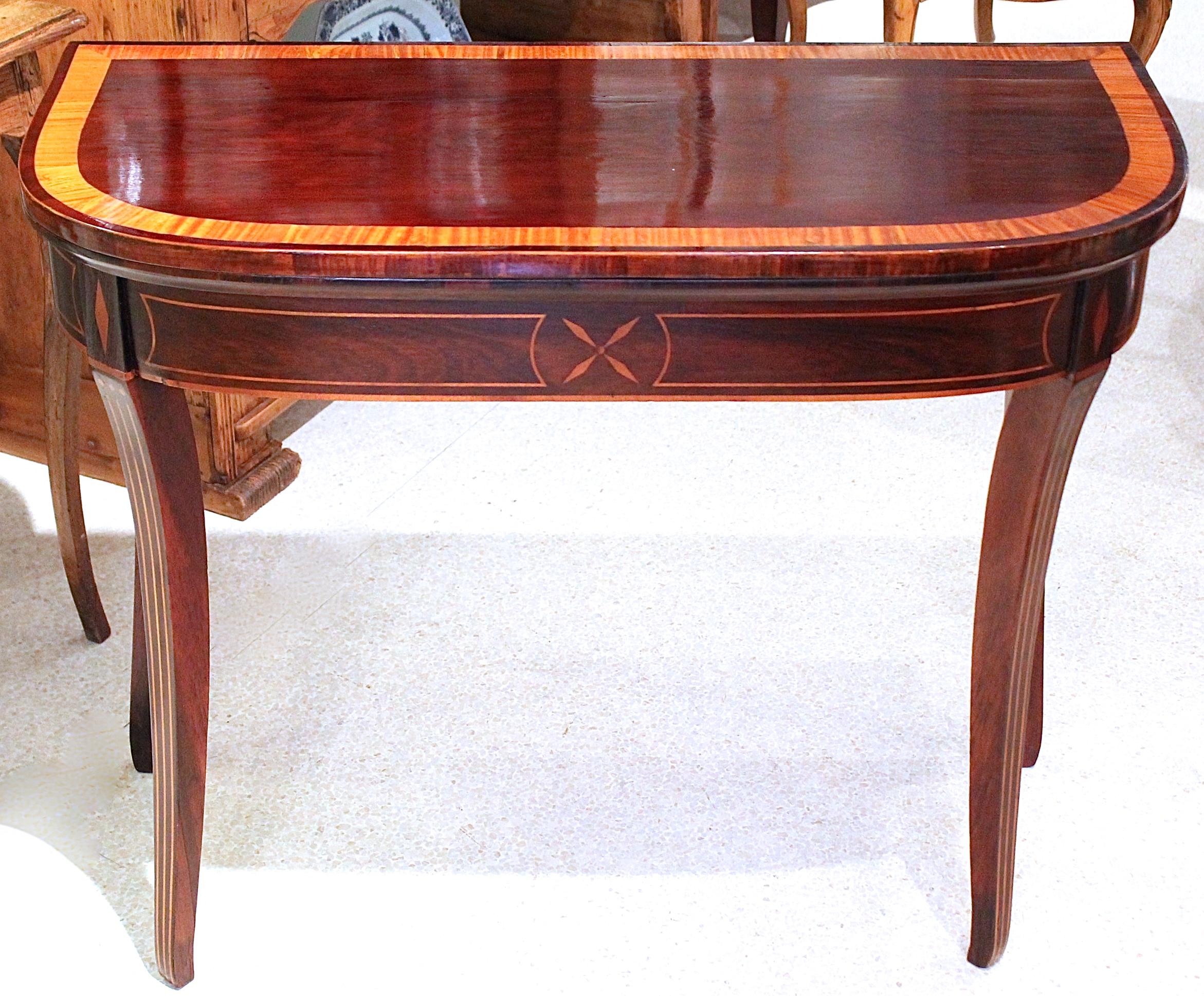 A stylish and unusual sabre leg D- shaped card table, boldly inlaid with contrasting satinwood. Ideal for a small console/side table. The top is both banded and strung with luminous satinwood, while the apron and all four legs have striking inlaid