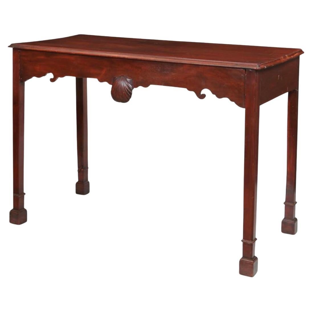 Table d'appoint George III de la fin du XVIIIe siècle à plateau rectangulaire, caractérisée par des lignes épurées et une riche finition en acajou. La table présente des bords sculptés sur la frise avec un décor de rinceaux et un cartouche central