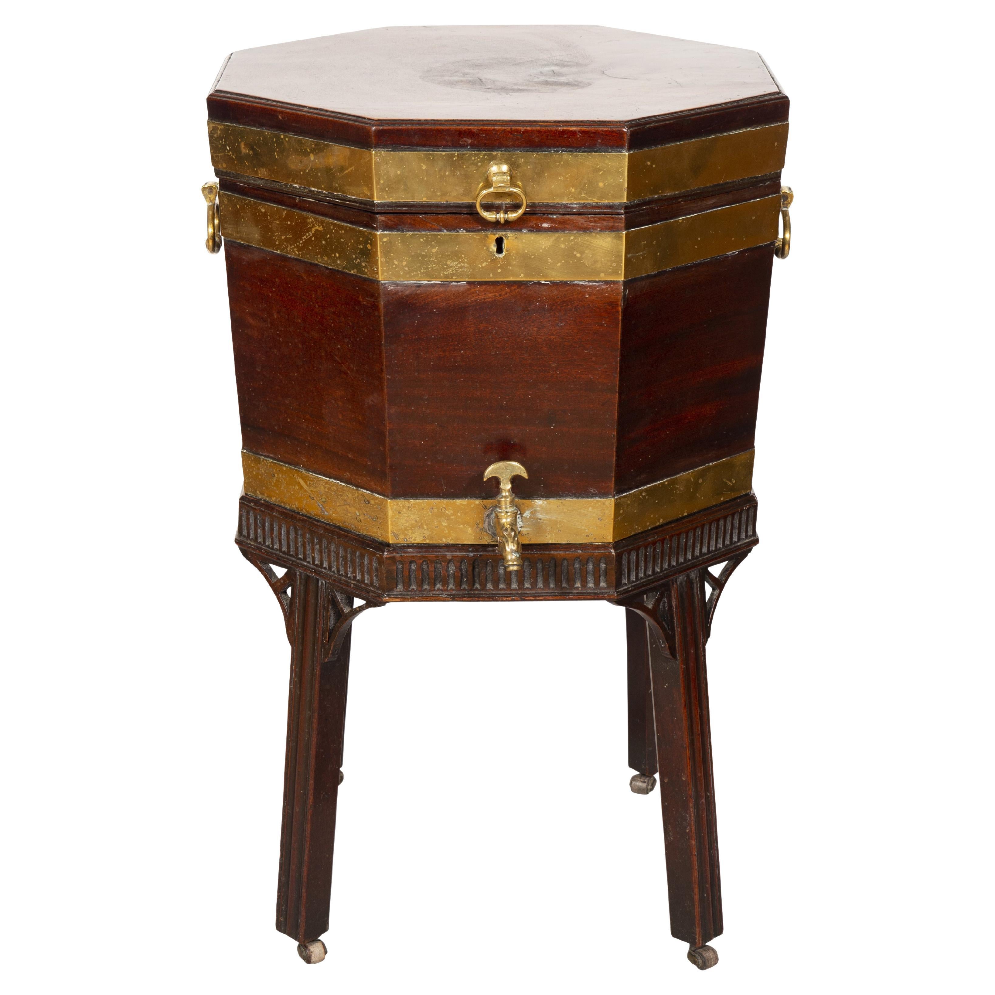 Octagonal hinged top opening to a lead lined compartment , conforming brass strapped case with spigot , base with fluted carved frieze and square molded legs and casters.