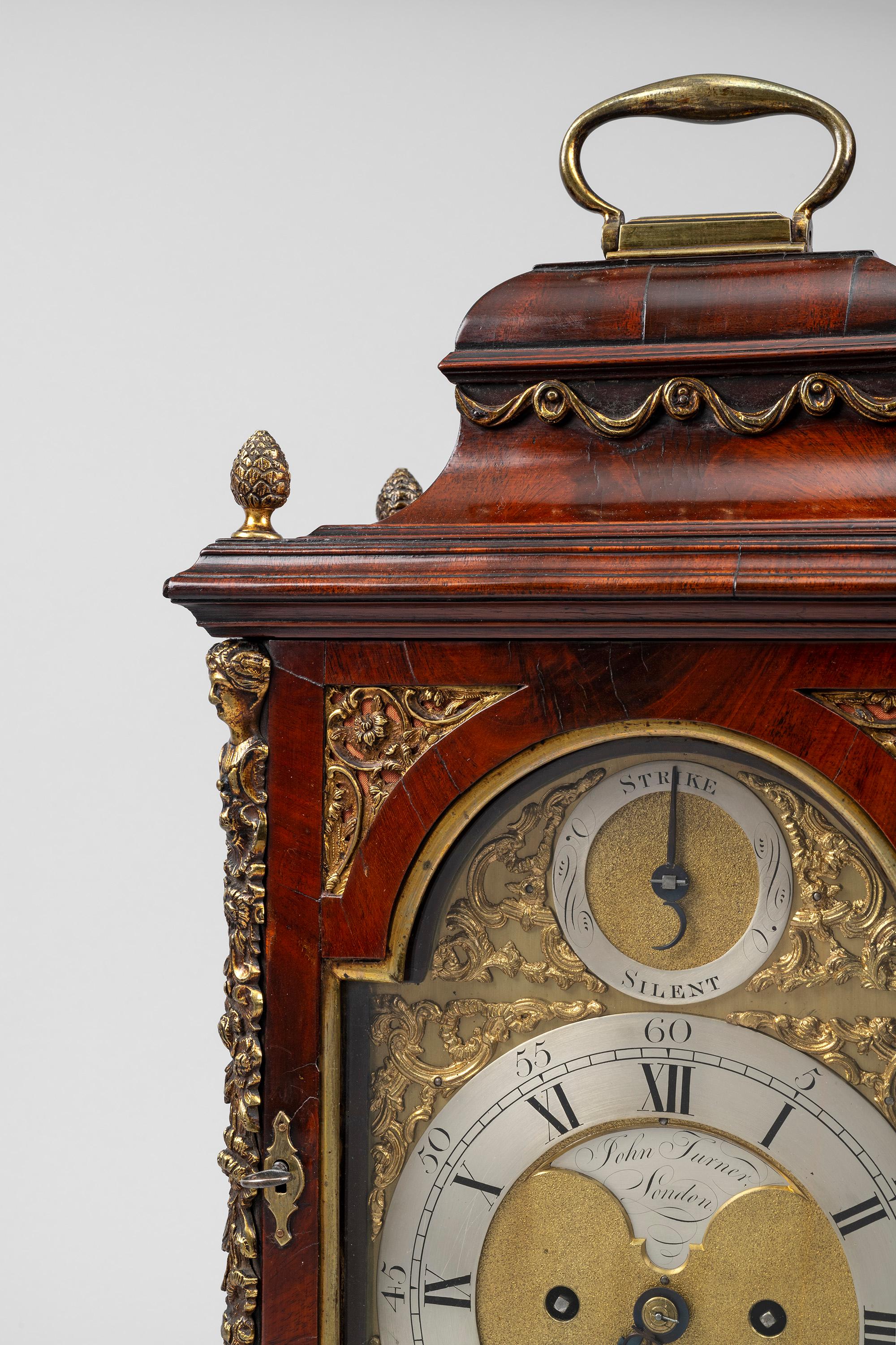 A George III period antique brass-mounted mahogany bracket clock by the London maker John Turner. 

The bell-top case with brass lined front door and brass side frets stands on brass bracket feet and is surmounted with a single brass carrying handle