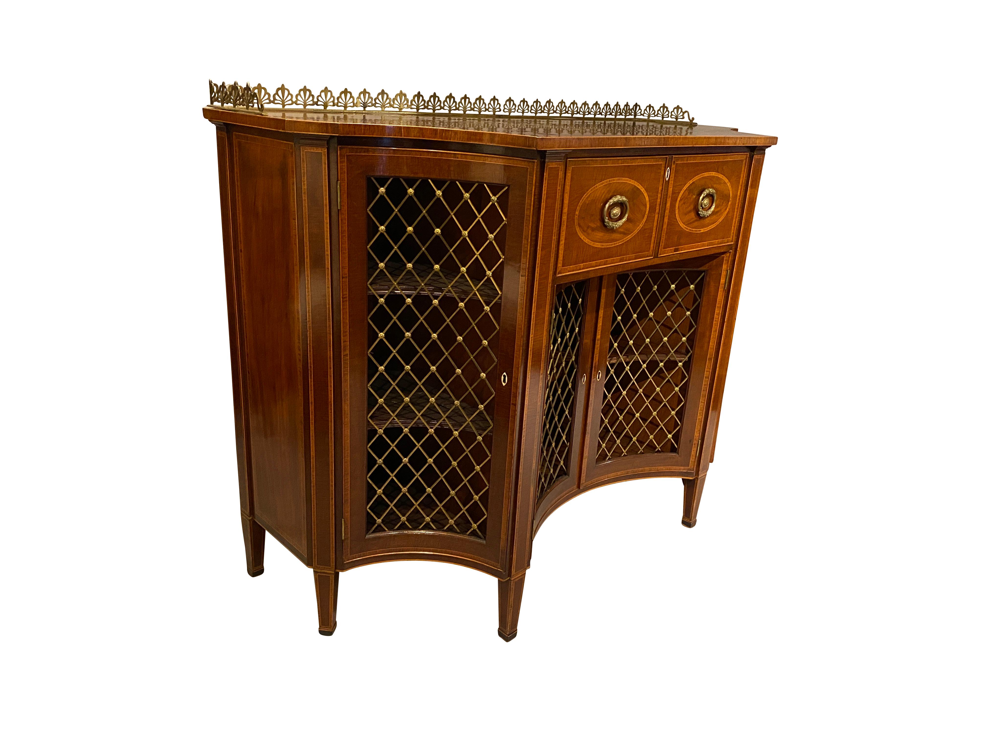 Most likely by Gillows of Lancaster. Rectangular top with concave corners, generous depth, with drawer opening to expose a fitted desk with drawers and cubbys over a pair of grill doors with false side doors, raised on square tapered legs. A finely