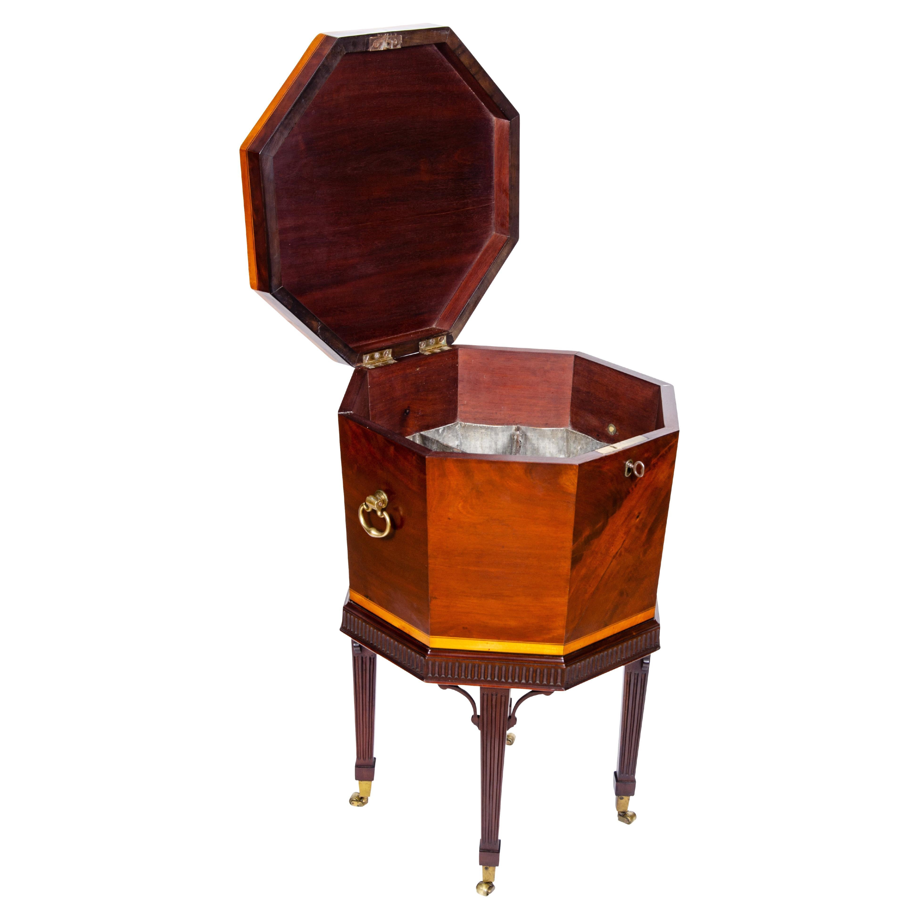 In very nice condition nicely French polished with fitted tin interior. Octagonal form with satinwood banding and central circular fan inlay. Hinged top. The base with reeded frieze and tapered reeded legs and casters.