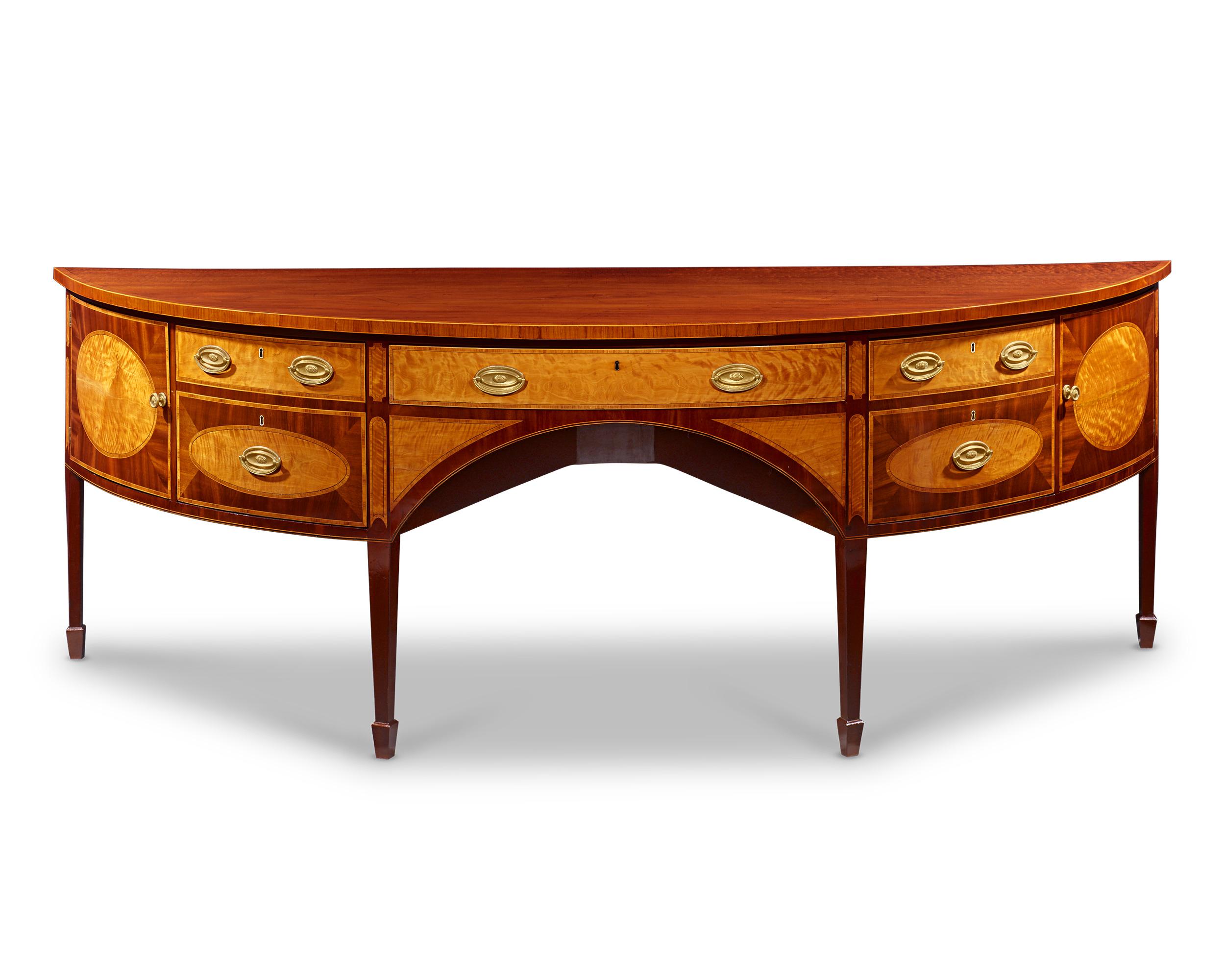 This magnificent demi-lune Georgian sideboard displays the pinnacle of the era’s refined craftsmanship and boasts a distinguished provenance. Crafted of the finest mahogany, the era's timber of choice for well-appointed manor homes, the sideboard is
