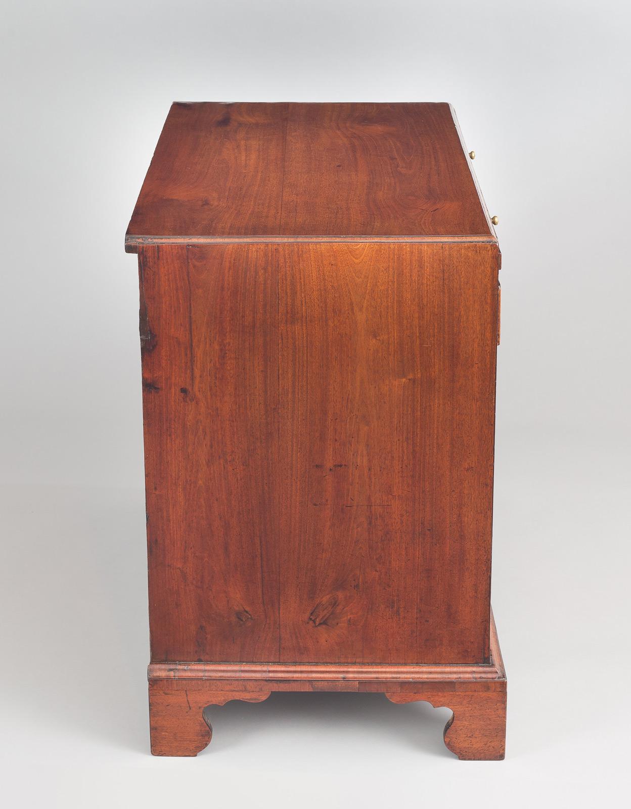 George III mahogany caddy-top bachelor’s chest with four graduated drawers, a brushing slide with green baize liner, original brass hardware, escutcheons and key, raised on shaped bracket feet. Beautiful patina and color.