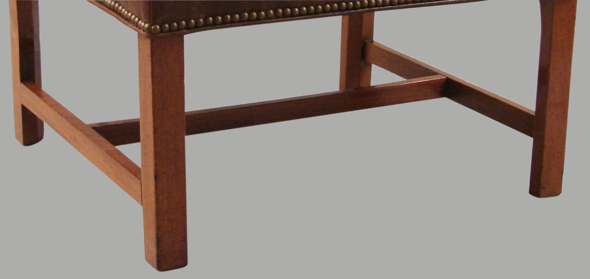 A substantial George III period mahogany stool, now upholstered in brown leather with brass nailhead trim, and an attached cushion resting on straight legs joined by an 