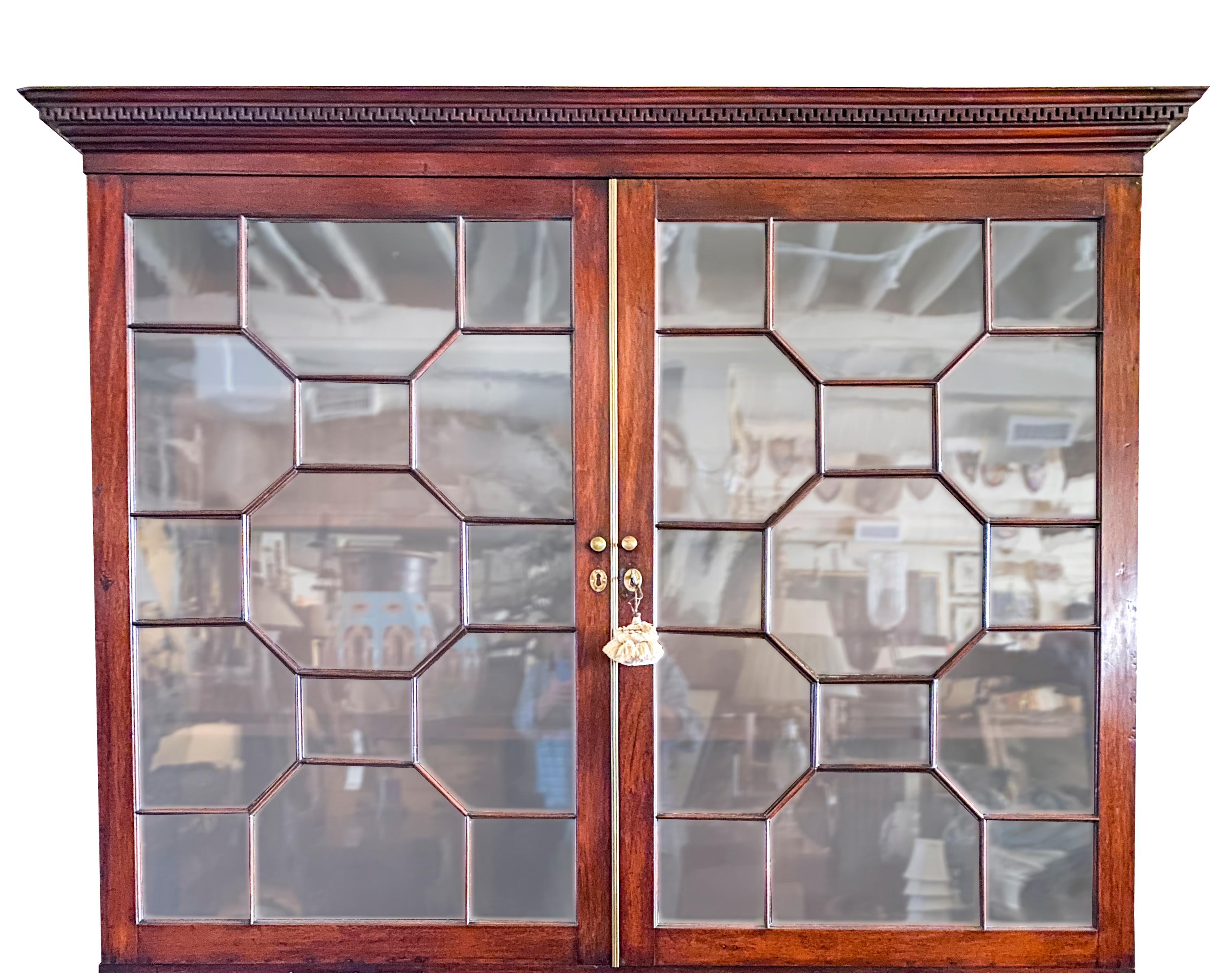 With rectangular dentilled cornice over a pair of doors with Chinese Chippendale mullions enclosing adjustable shelves over a double hinged paneled door and a single paneled door. Plinth base. Keys.