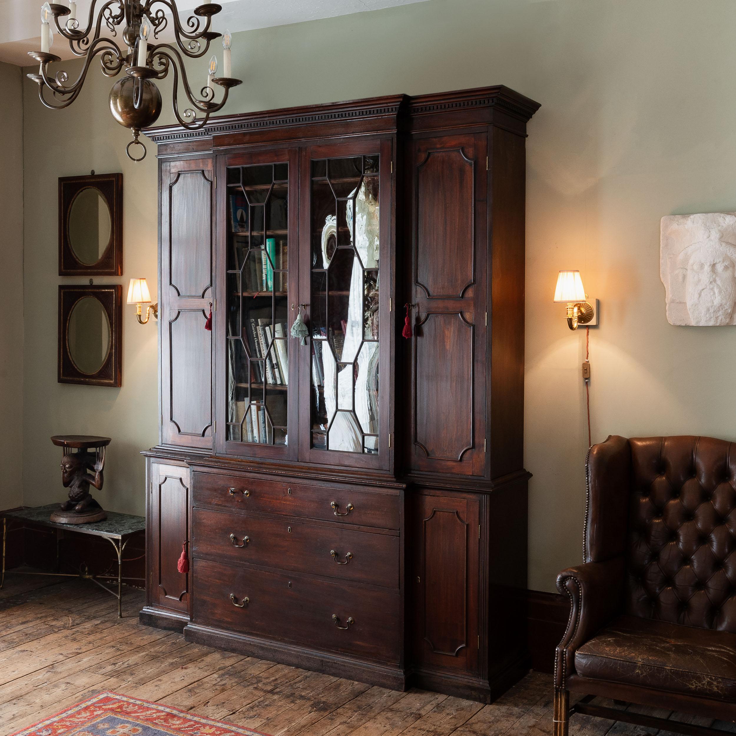Libreria in mogano di Giorgio III a forma di fronte, con cornice a dentelli sopra il mobile centrale vetrato a traforo con ante a campo su entrambi i lati, tutte contenenti scaffali regolabili, la base con tre ante graduate.


Dimensioni:	253cm