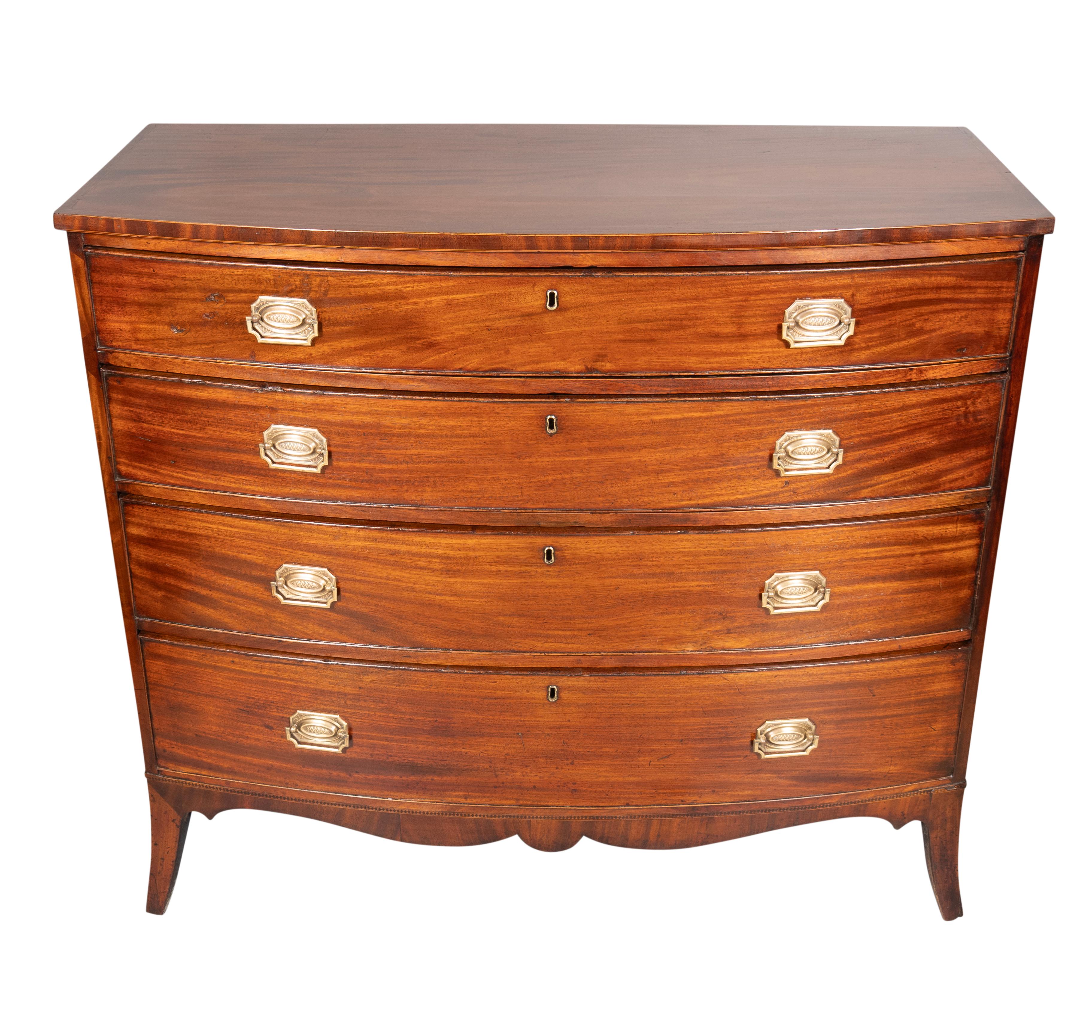 With a rectangular bowed top with string inlay over four graduated drawers with later replaced brass handles. Splayed feet. With key.