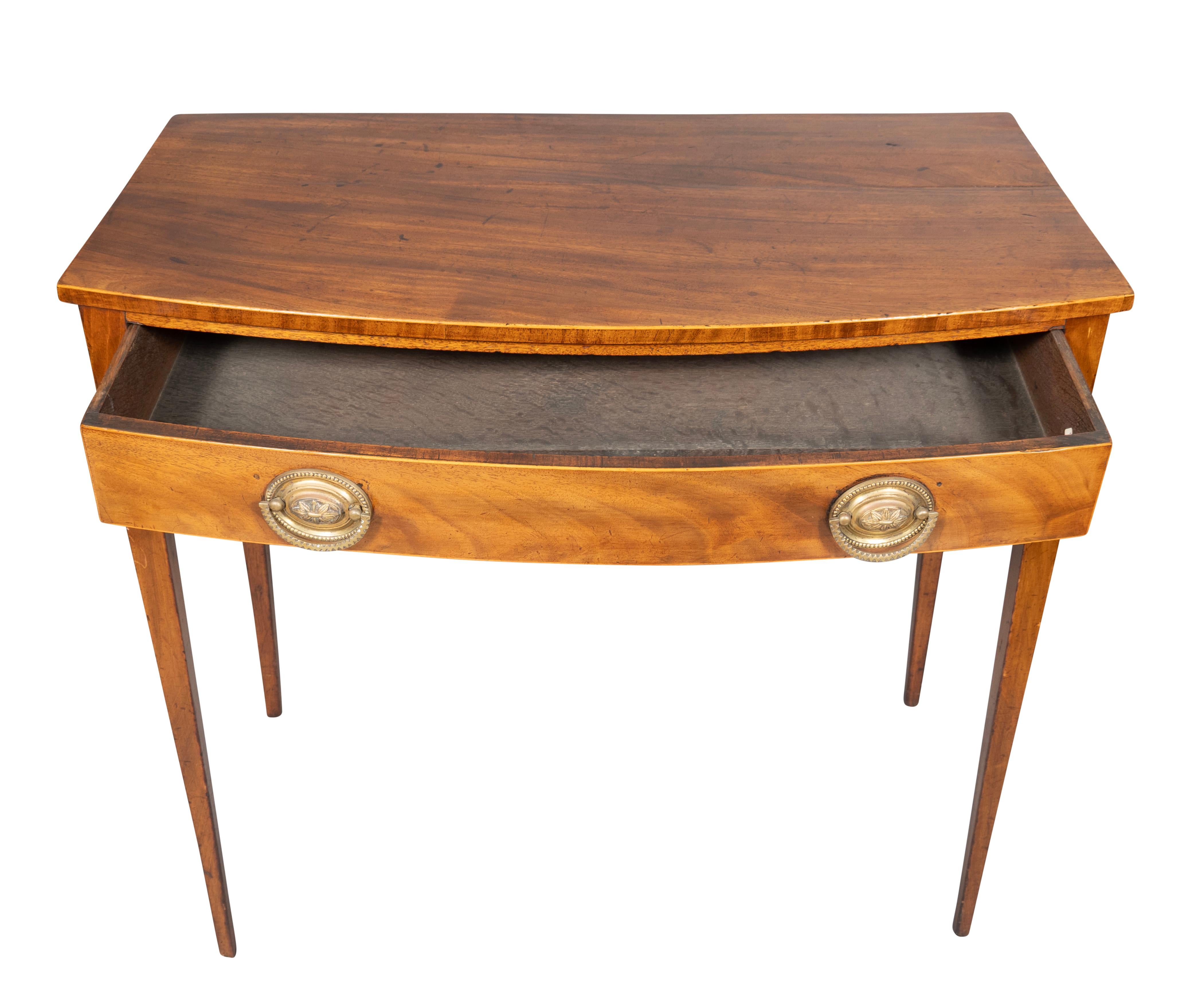 Rectangular bowed top over a drawer with oval brass handles. Square tapered legs.
