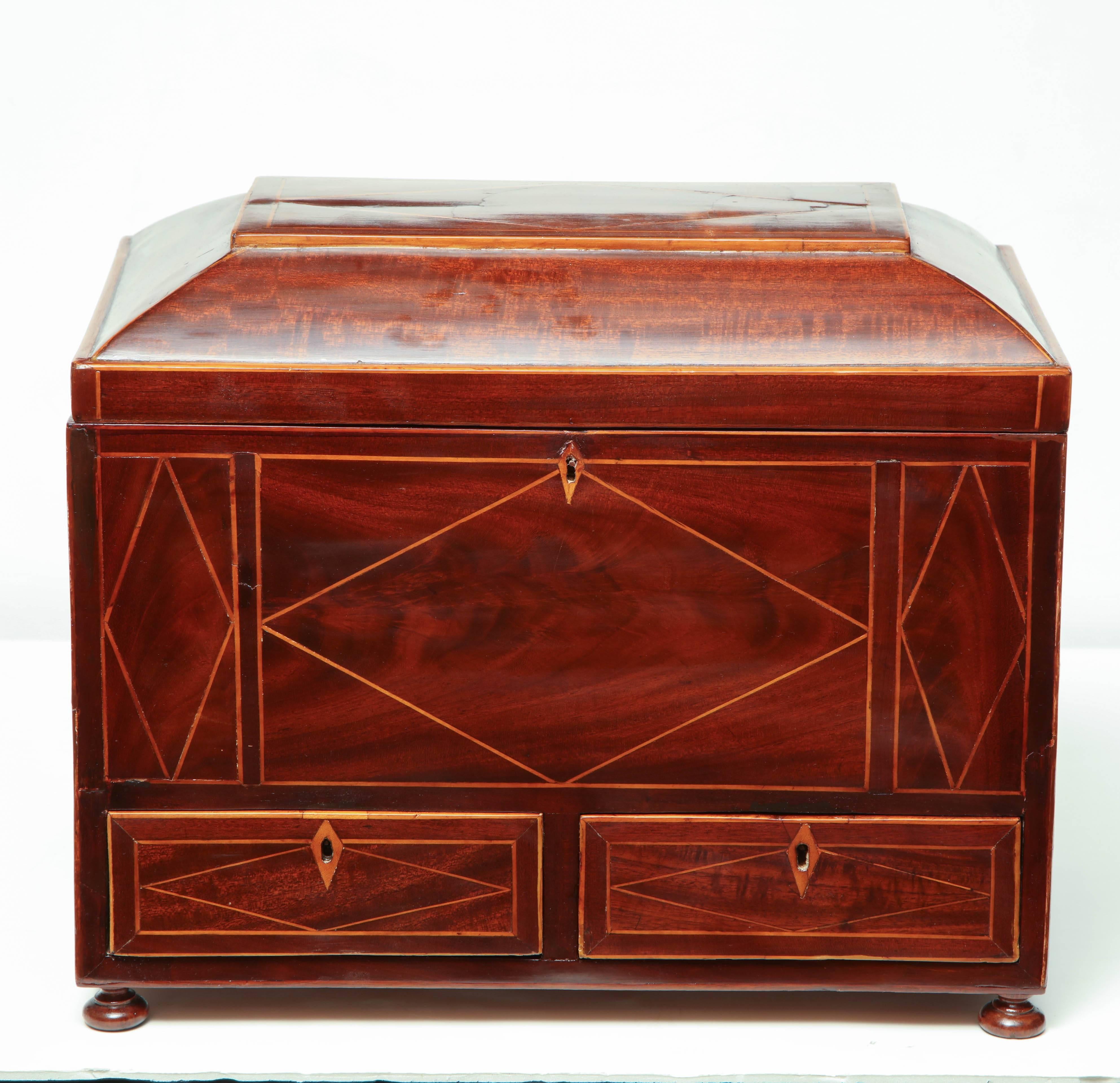 George III mahogany and satinwood line inlaid box with a fitted interior, multiple drawers and brass handles and raised on ball feet.