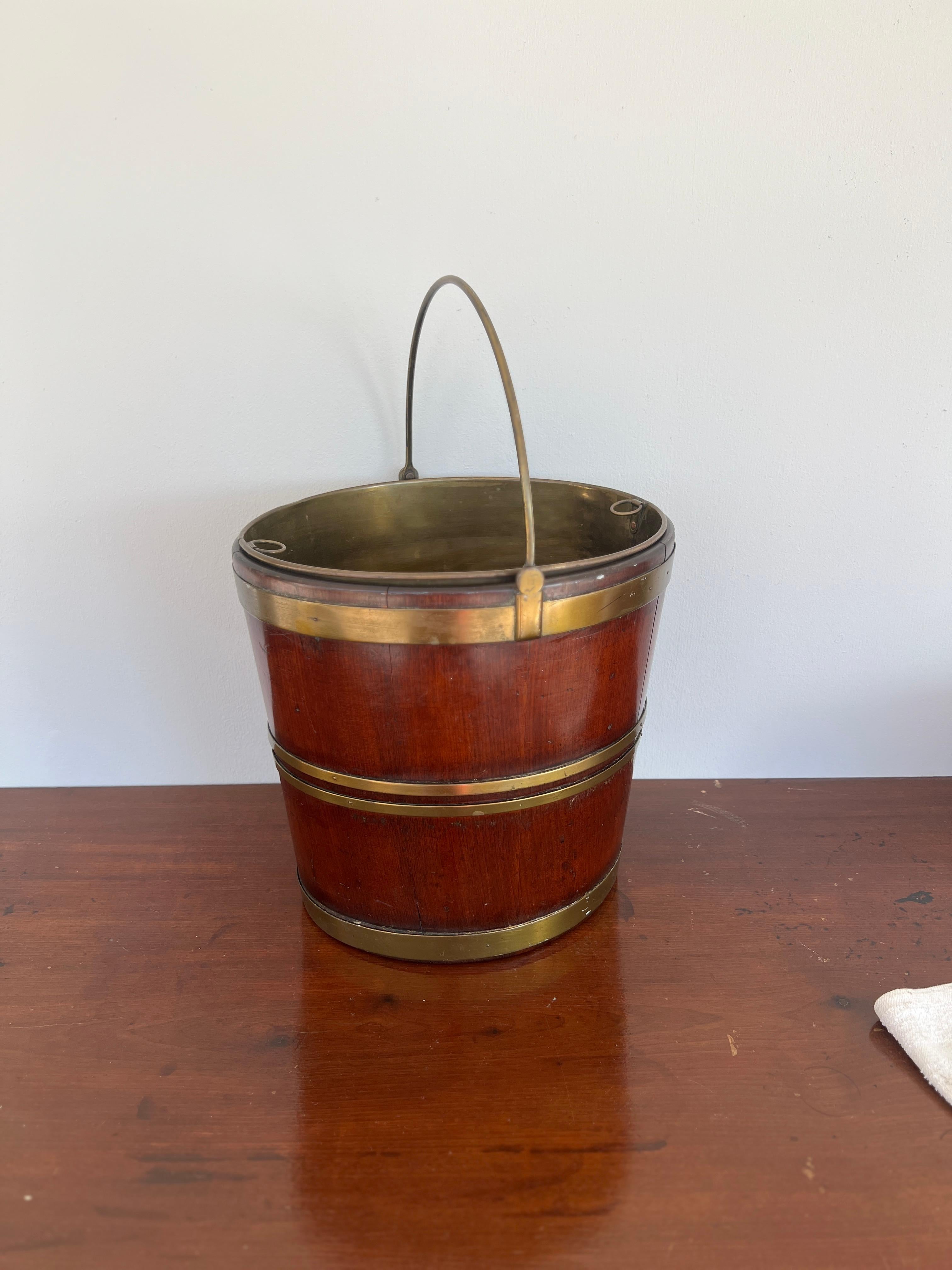 Continental, likely English.

A George III circa 1800 peat, turf, coal or kindling bucket of near round form and confirming body mounted with brass straps. A handle is affixed and the original brass liner accompanies the bucket. Works great against