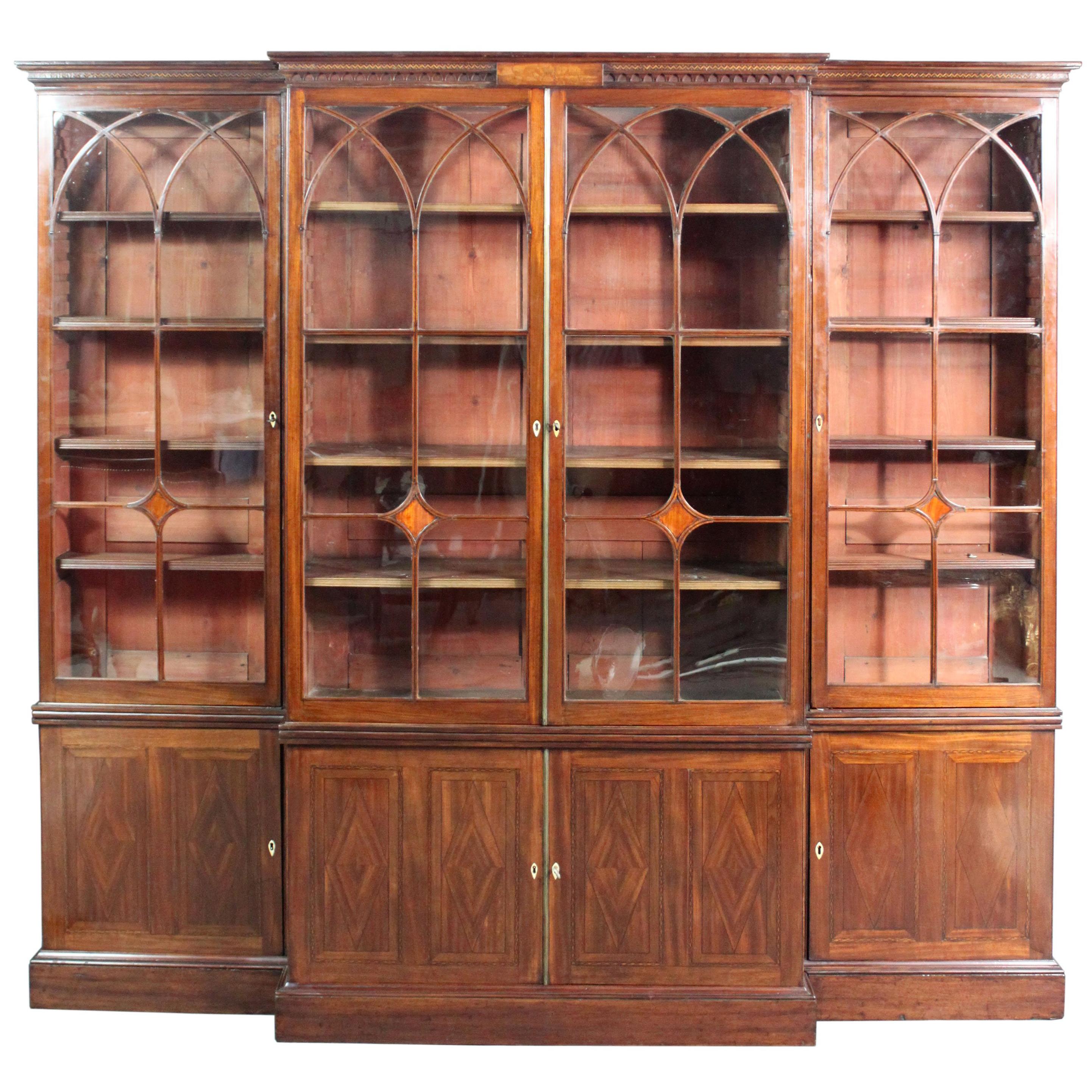 A George III Sheraton period mahogany breakfront bookcase of good low-waisted proportions, attractive arched glazing bars inlaid with ebony and satinwood diamonds which match the inlaid diamonds in the doors of the base, dismantles into 3 vertical
