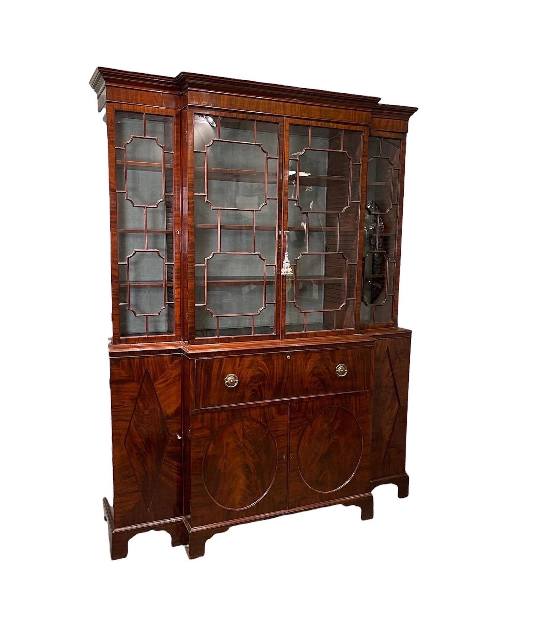 This exceptional George III Mahogany Breakfront Bureau Bookcase with Glazed Doors, has wonderful flame & crotch grain Mahogany. Comprised of a large central cabinet, flanked by 2 smaller cabinets all Lined in green silk. It’s doors have mullions in
