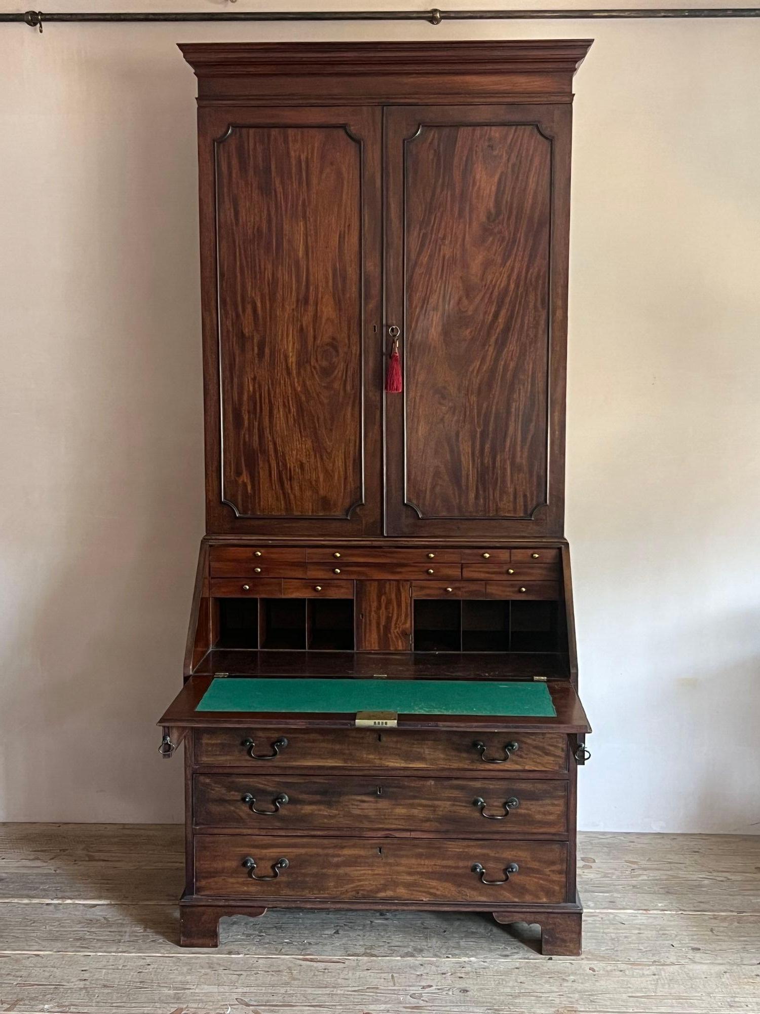 Ein Mahagoni-Bücherregal aus der Zeit von George III. Mit einem geformten Gesims über zwei feldartigen getäfelten Türen, die sich öffnen, um vier verstellbare Regale im Inneren mit einem inneren Schrank zu offenbaren, die Kommode fallen, um ein
