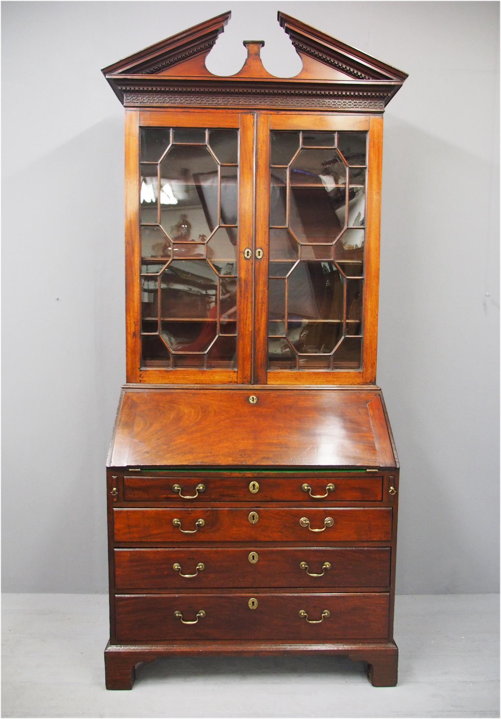 Early George III mahogany bureau bookcase, circa 1770. The moulded dentil cornice is surmounted by a ‘broken’ pediment over a blind fretwork frieze. The astragal glazed doors has original glazing and glazing bars and inside are sliding adjustable