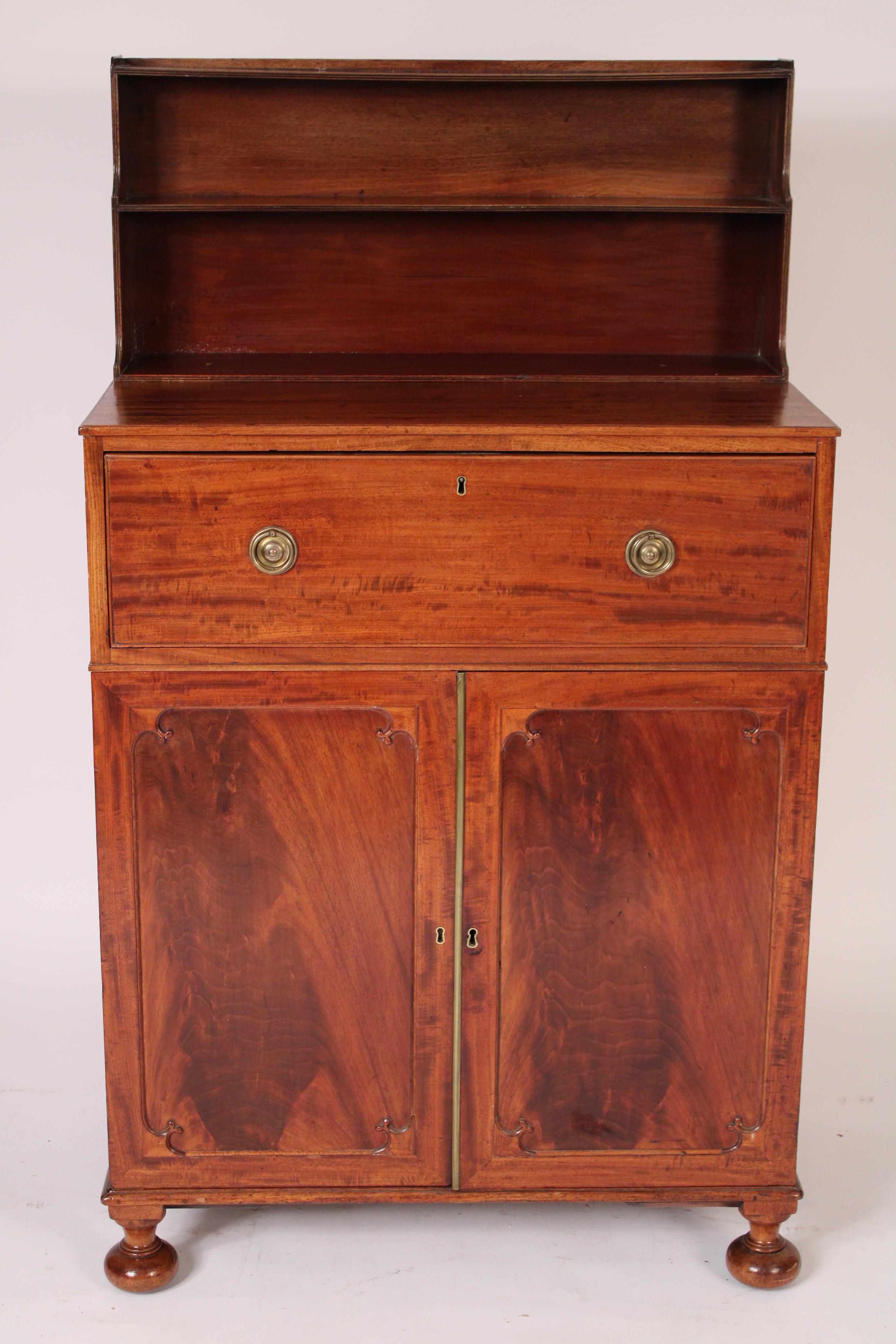 George III mahogany butlers desk, early 19th century. With a two shelf display rack, a plum pudding mahogany top, a plum pudding mahogany drawer that folds down to a leather writing surface, the interior of the desk with central cubby holes flanked