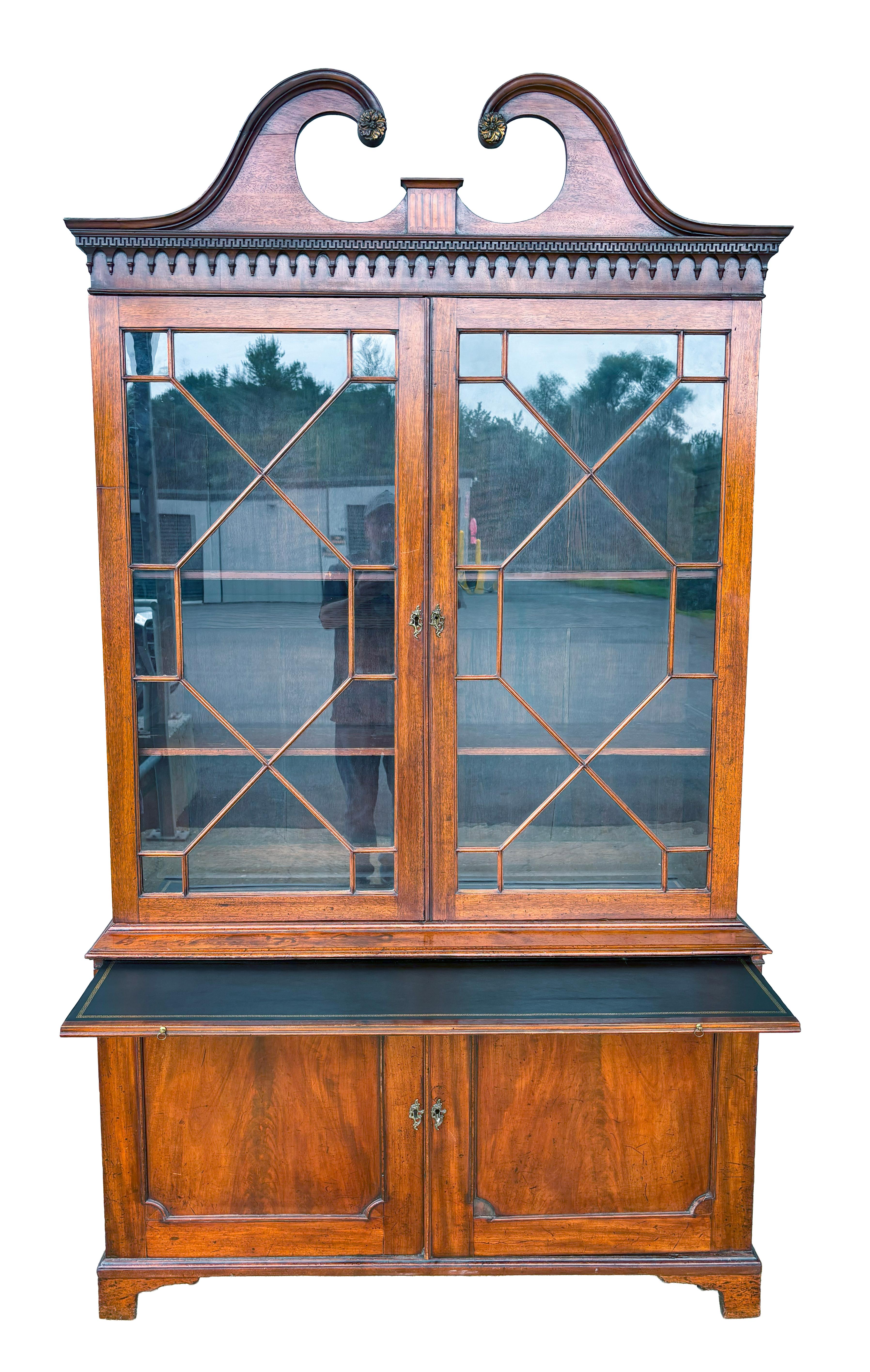 With an arched pediment over a pair of mullioned doors in the Chinese Chippendale taste. The lower section with a pair of cabinet doors. Bracket feet. Includes three shelves and keys.