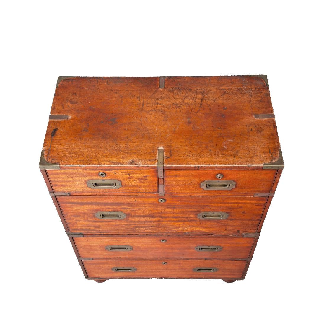 Early 19th century English five drawer mahogany campaign chest of unusual small size. Made in two sections and on turned feet, the top section with two short drawers over one long drawer and the lower section with two long drawers. Each drawer front